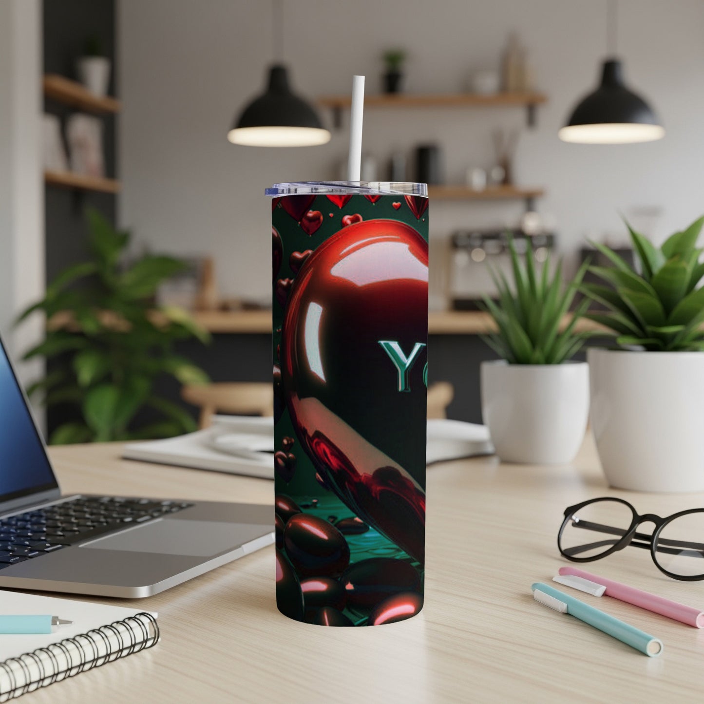 Tumbler with red hearts and "You" text on a desk with a laptop.