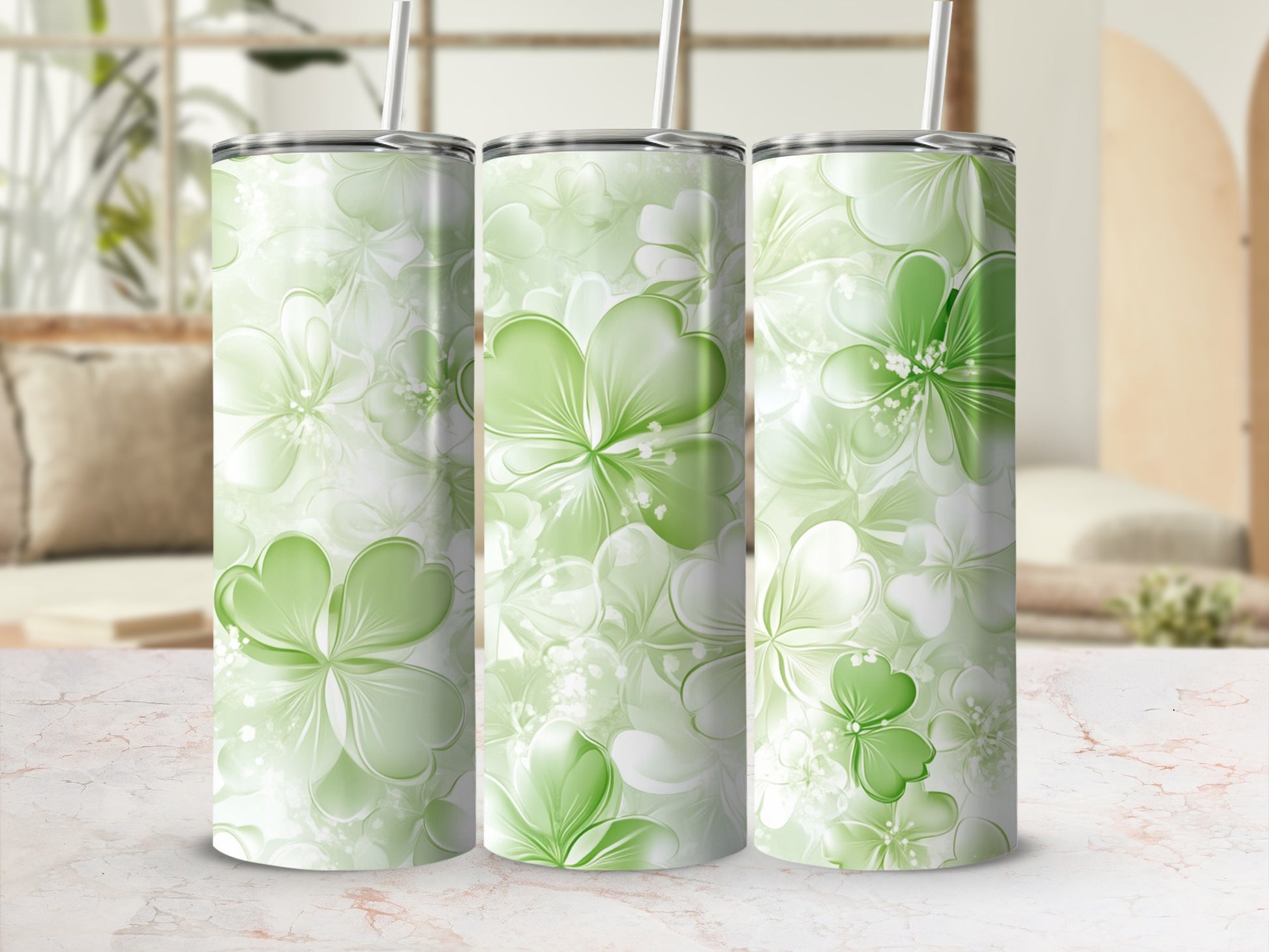 Three green floral tumblers with shamrock designs on a marble surface.