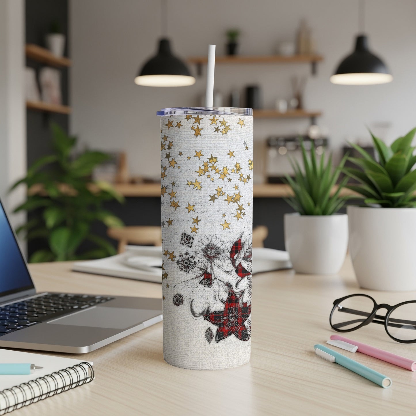 White tumbler with gold stars and floral design on a desk.