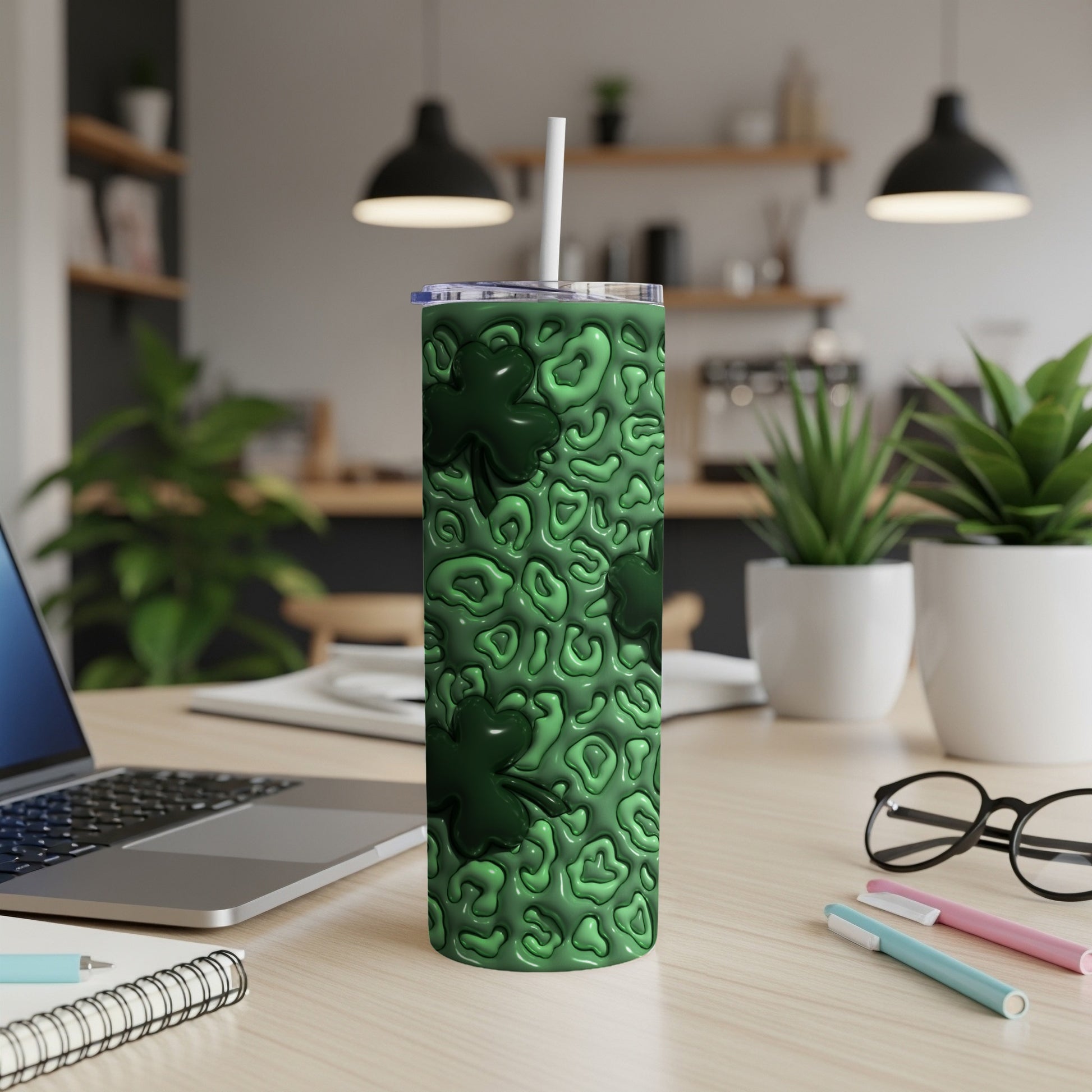 Green textured tumbler with shamrock pattern on a desk.