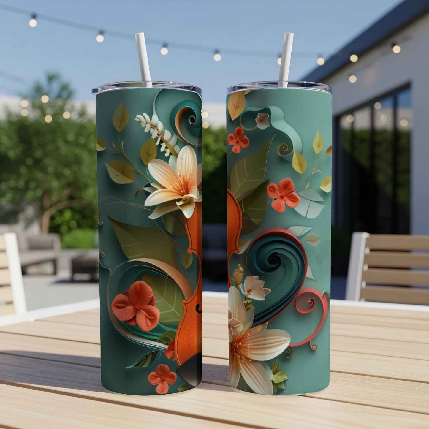 Two teal tumblers with floral and violin scroll designs on an outdoor table.