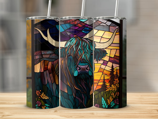 Stained glass Highland cow tumbler with straw, set against a woodland sunset.