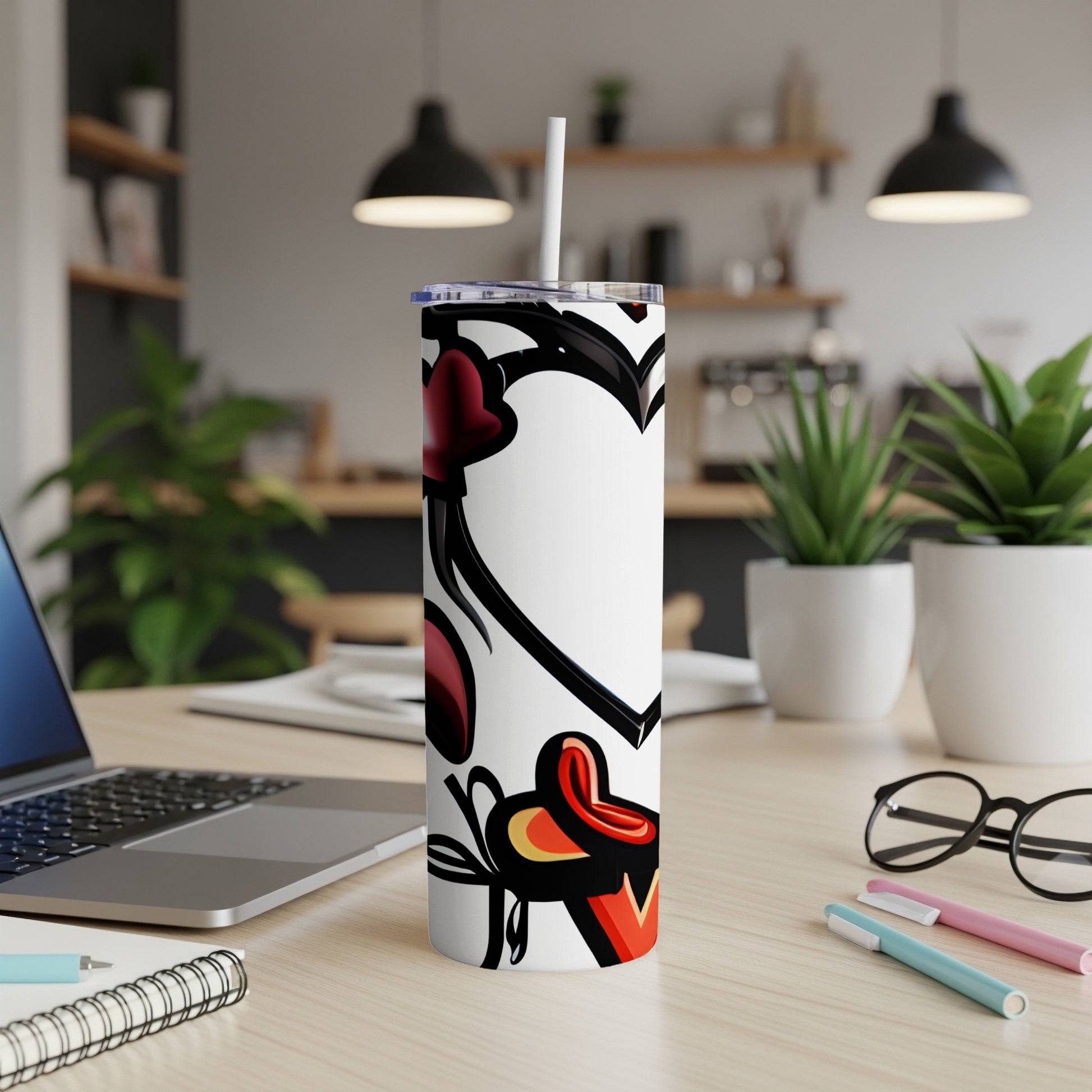White tumbler with red hearts and abstract black designs, straw included.