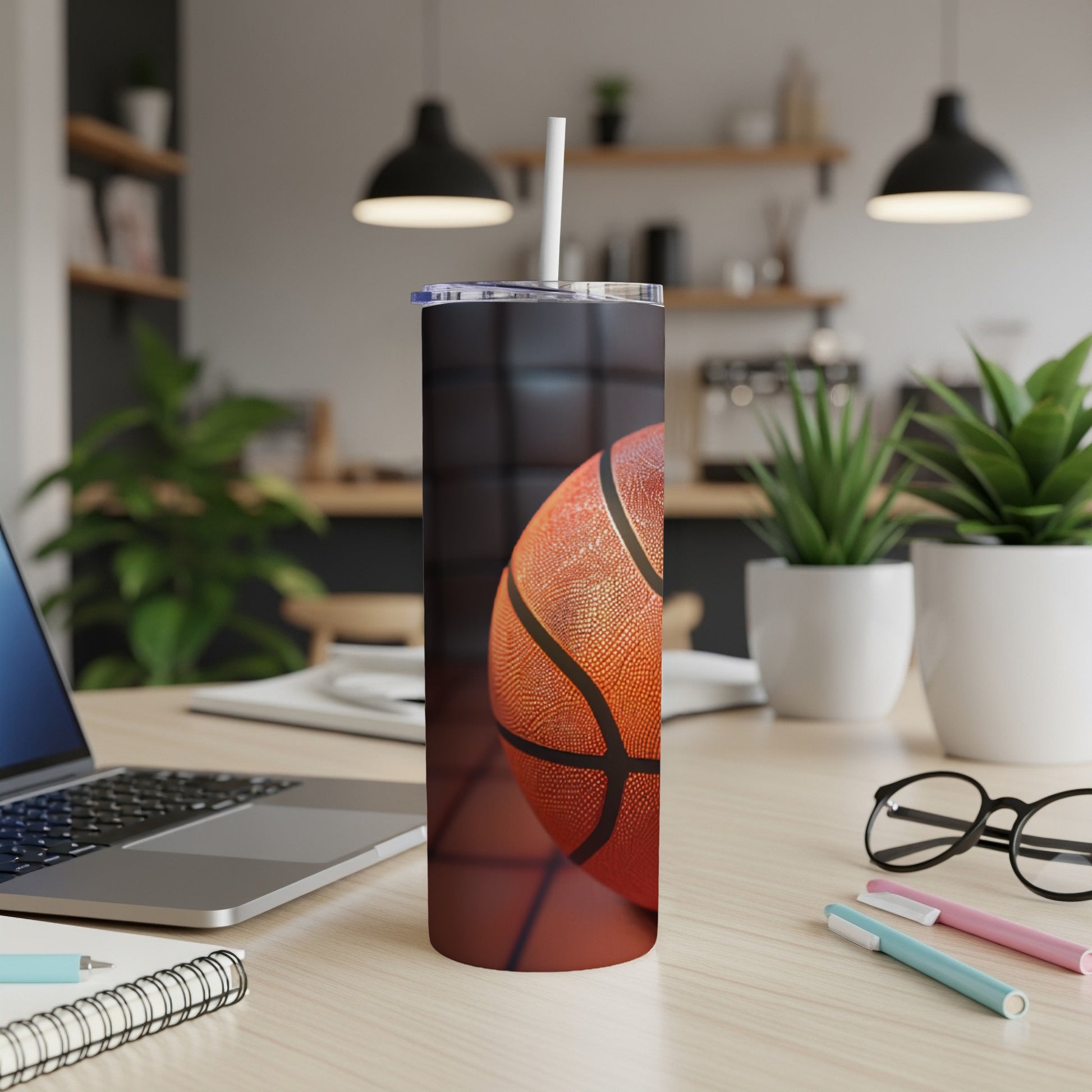 Basketball tumbler with straw on a desk next to a laptop.
