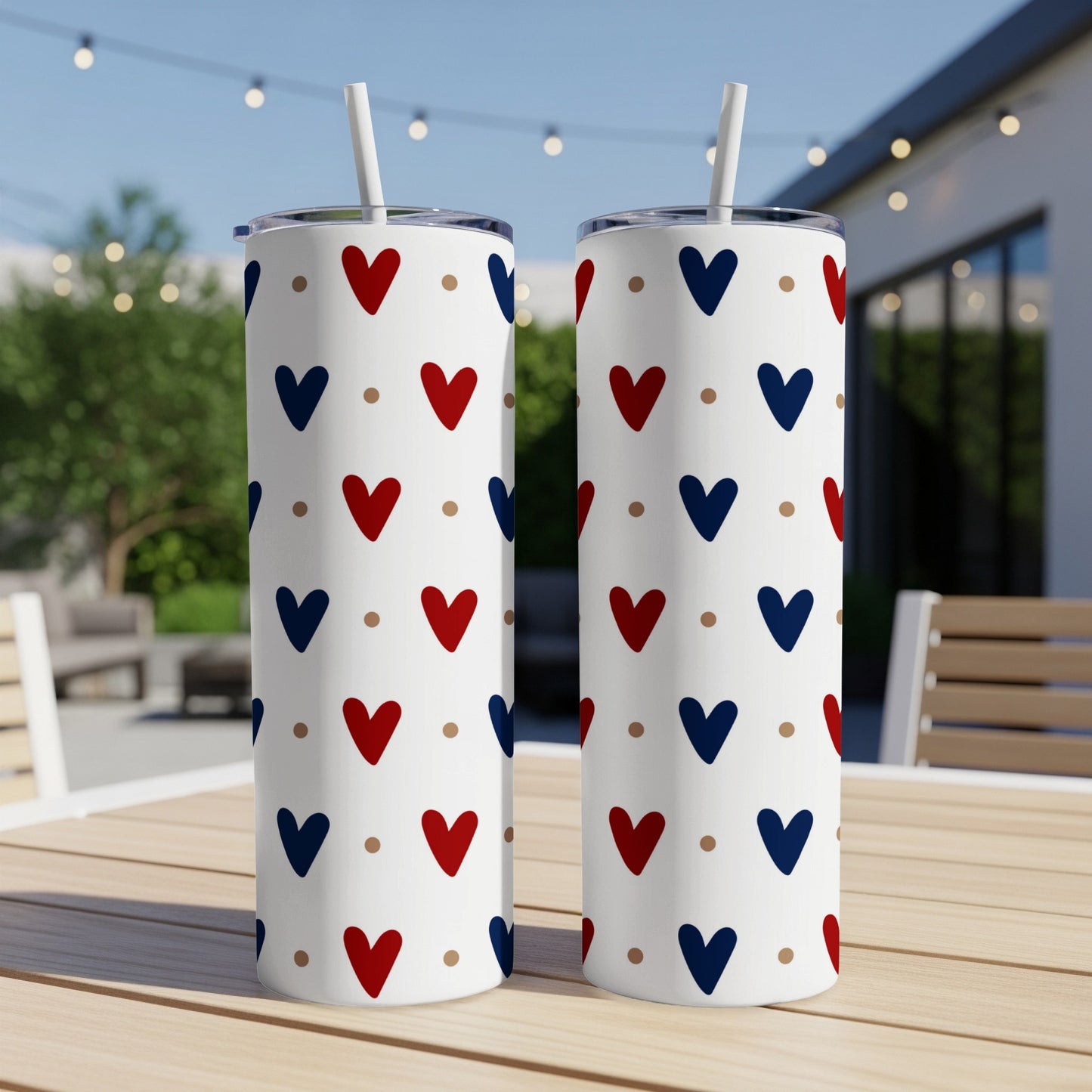 Two tall tumblers with red and blue heart pattern on outdoor table.
