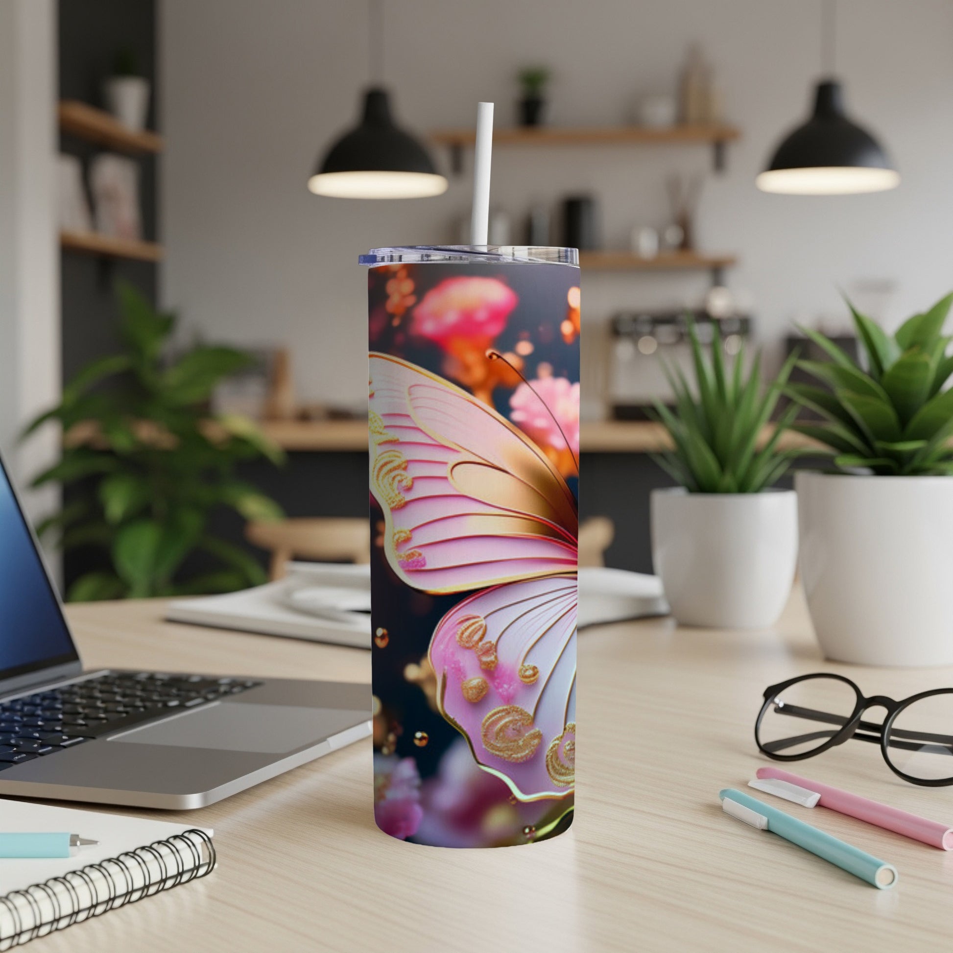 Pink and gold butterfly tumbler with straw on a desk.