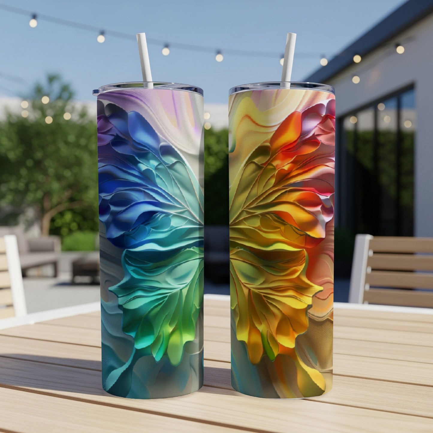Two colorful abstract patterned tumblers with straws on a wooden table.