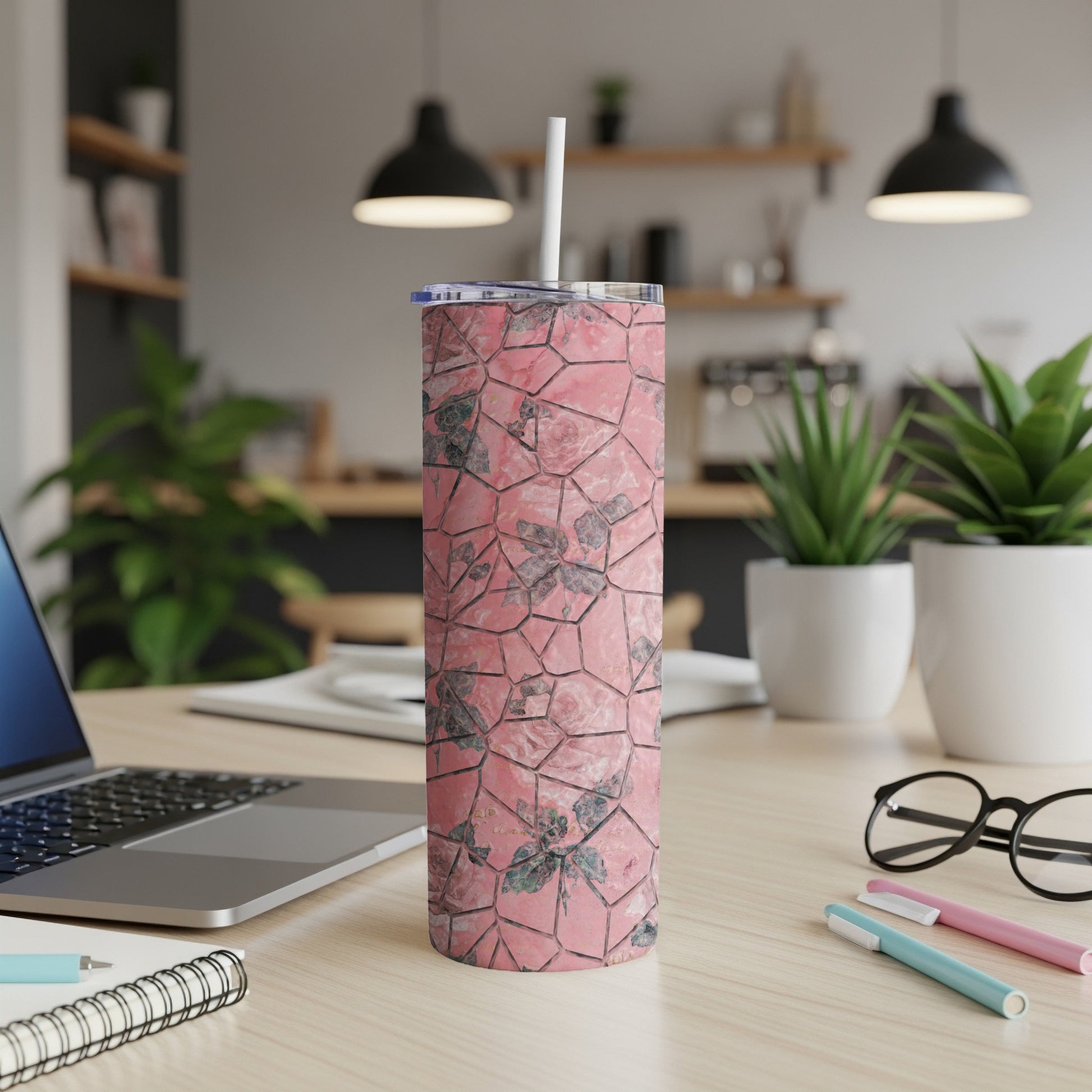 Pink floral patterned tumbler with straw on a desk.