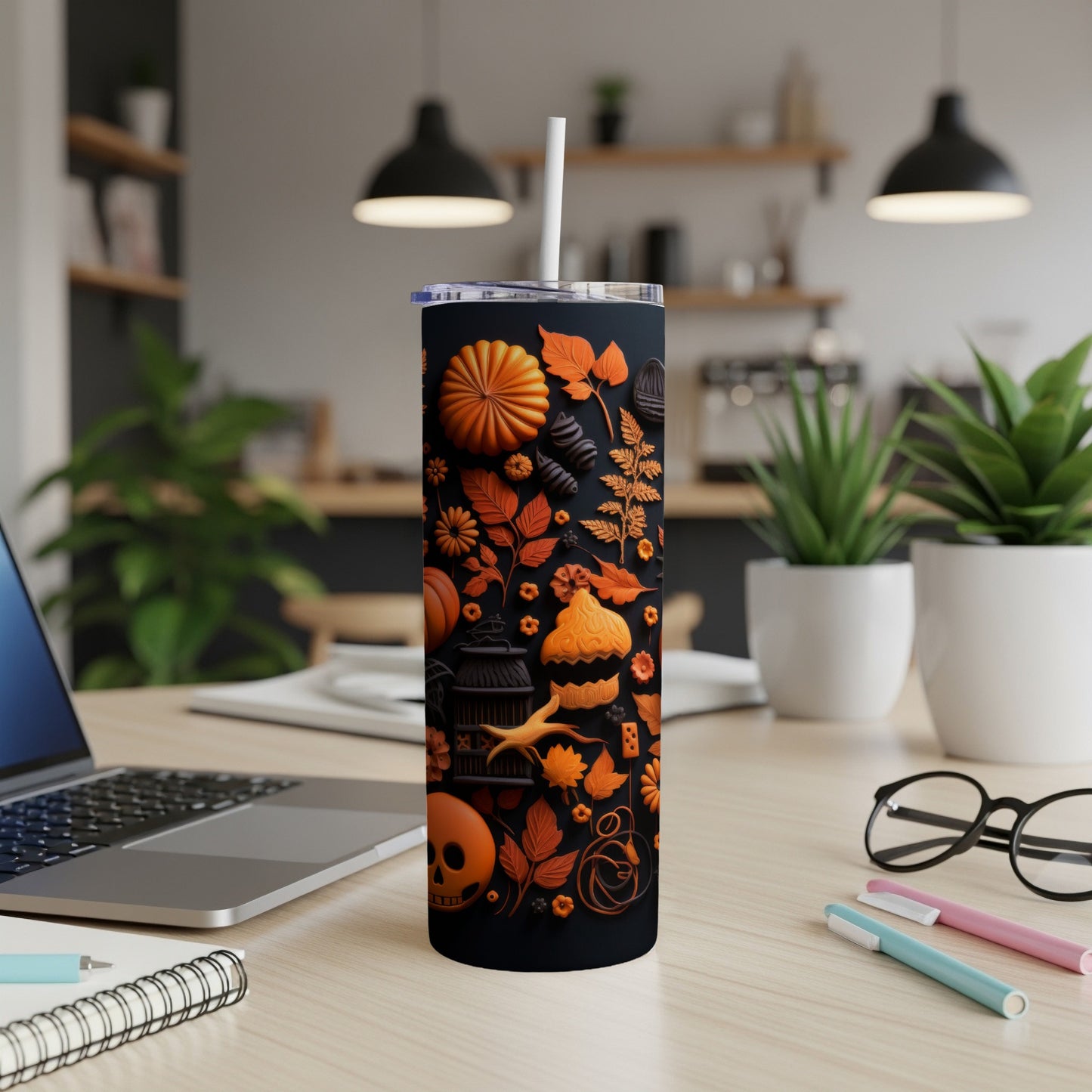 Black tumbler with orange Halloween-themed illustrations of pumpkins, leaves, and skulls.