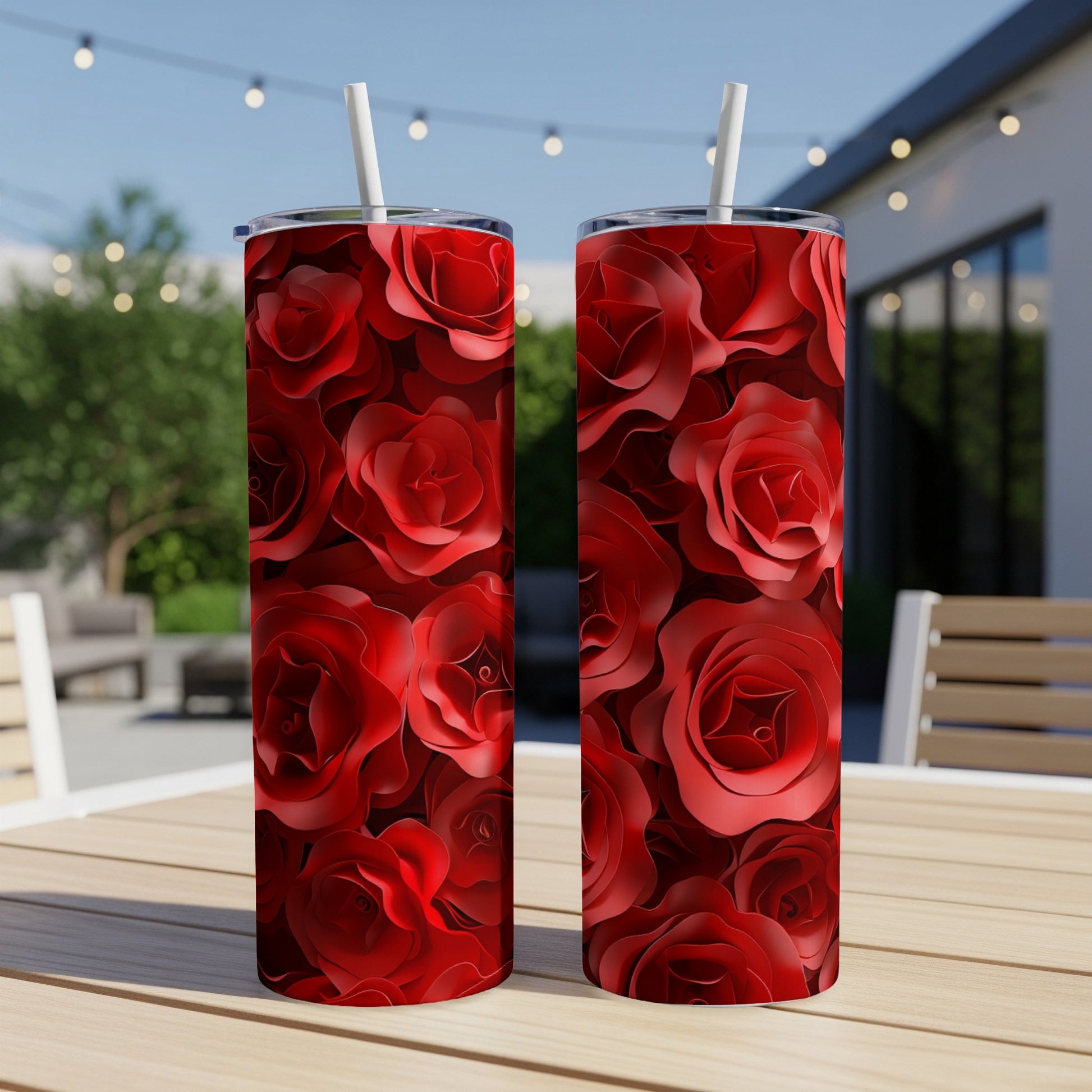 Two red rose-patterned tumblers with straws on a table.