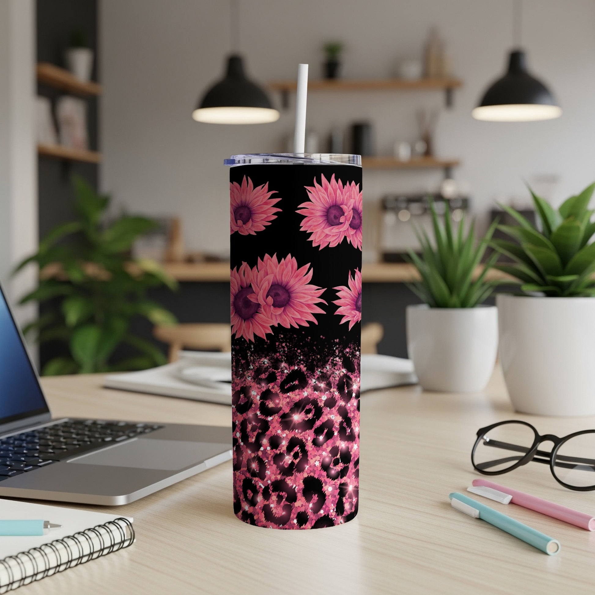 Pink floral and leopard print tumbler with straw on desk.