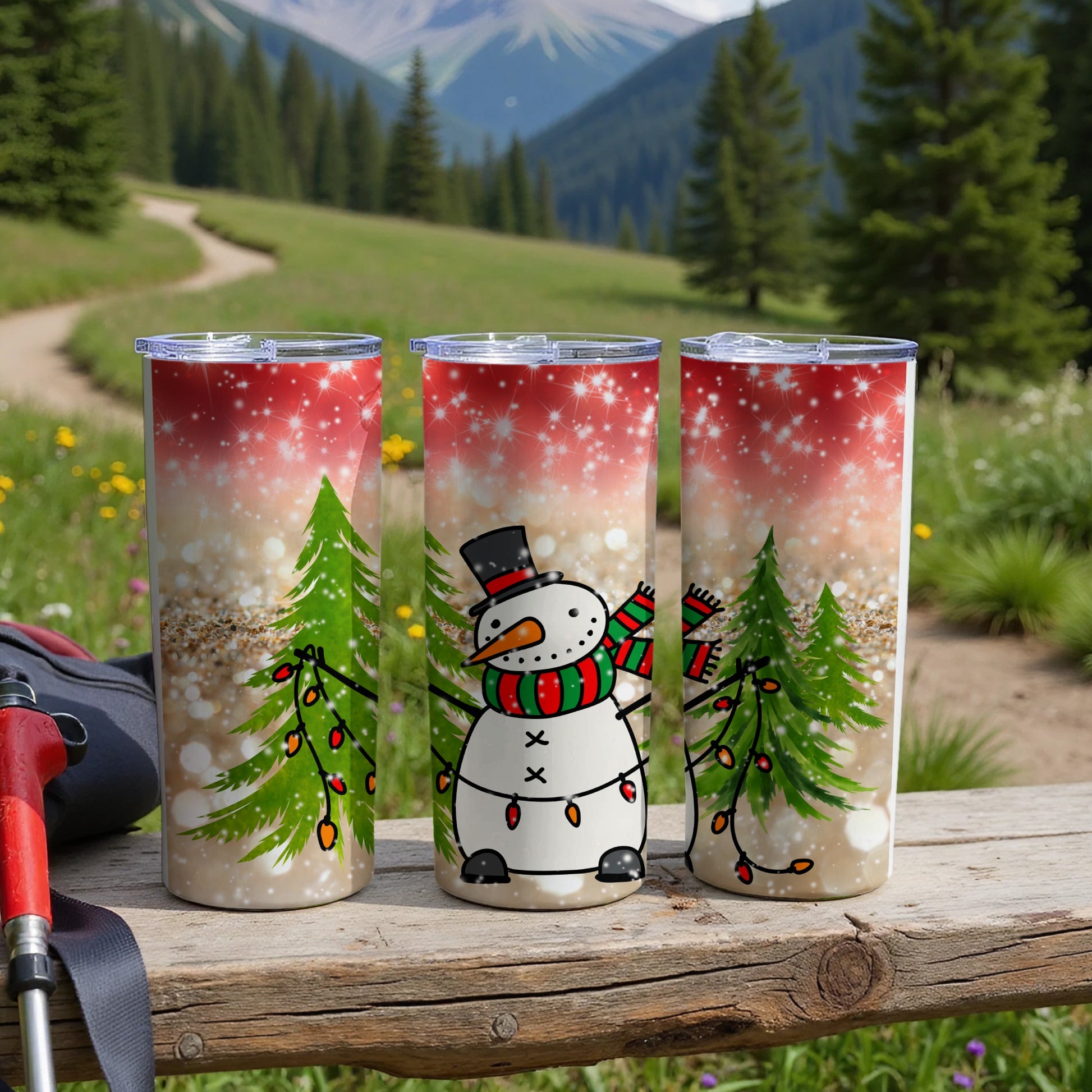 Three tumblers with snowman and Christmas tree design on a wooden surface.
