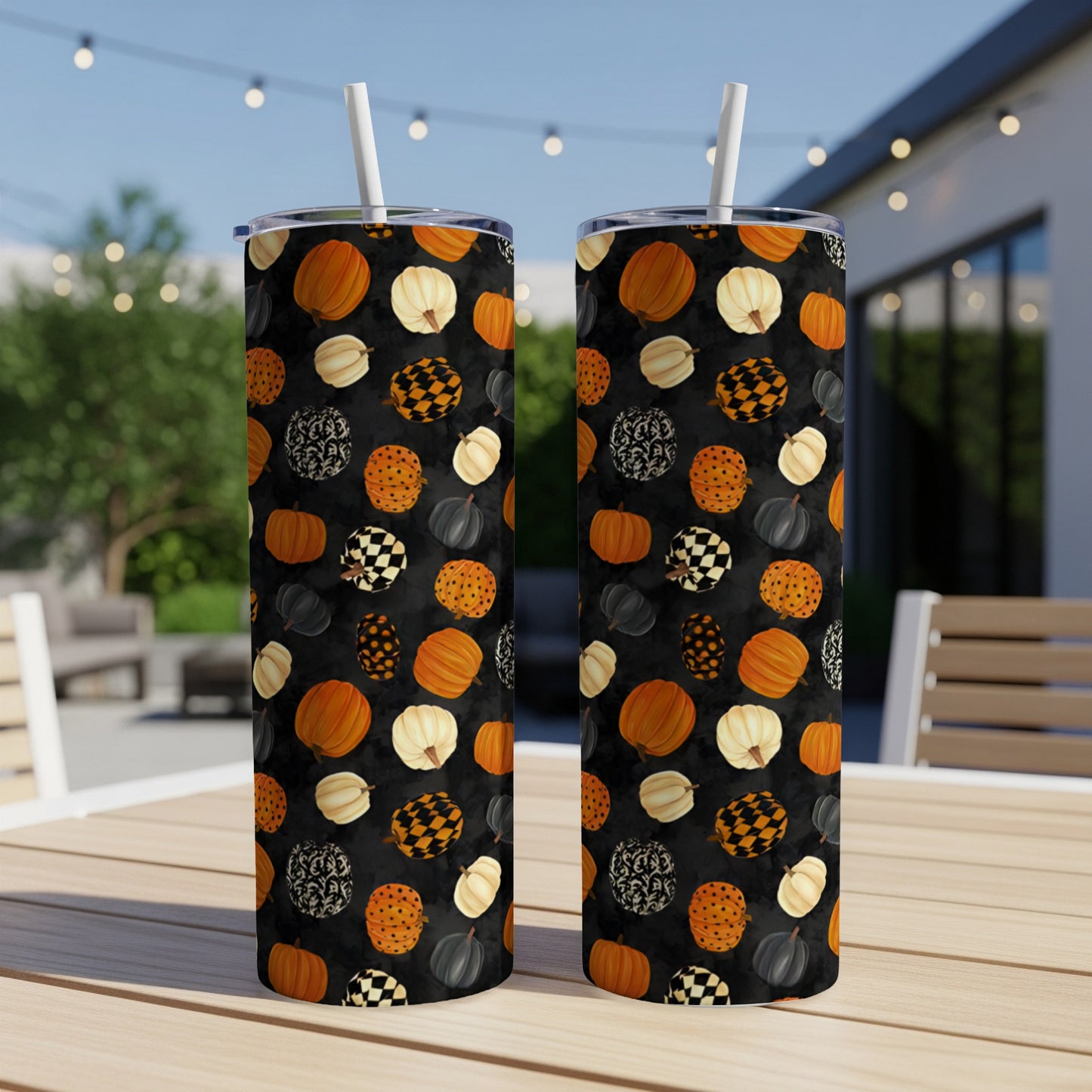 Two tumblers with a black background and a pattern of pumpkins, checkerboard, and floral shapes.
