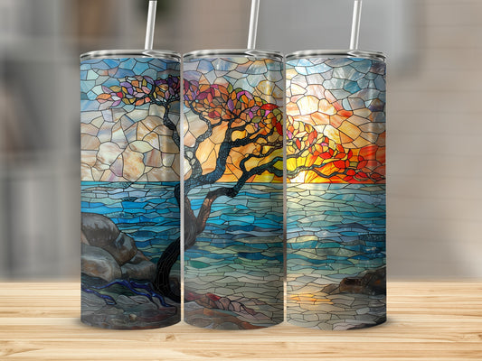 Stained glass tumbler with sunset scene over ocean and tree.