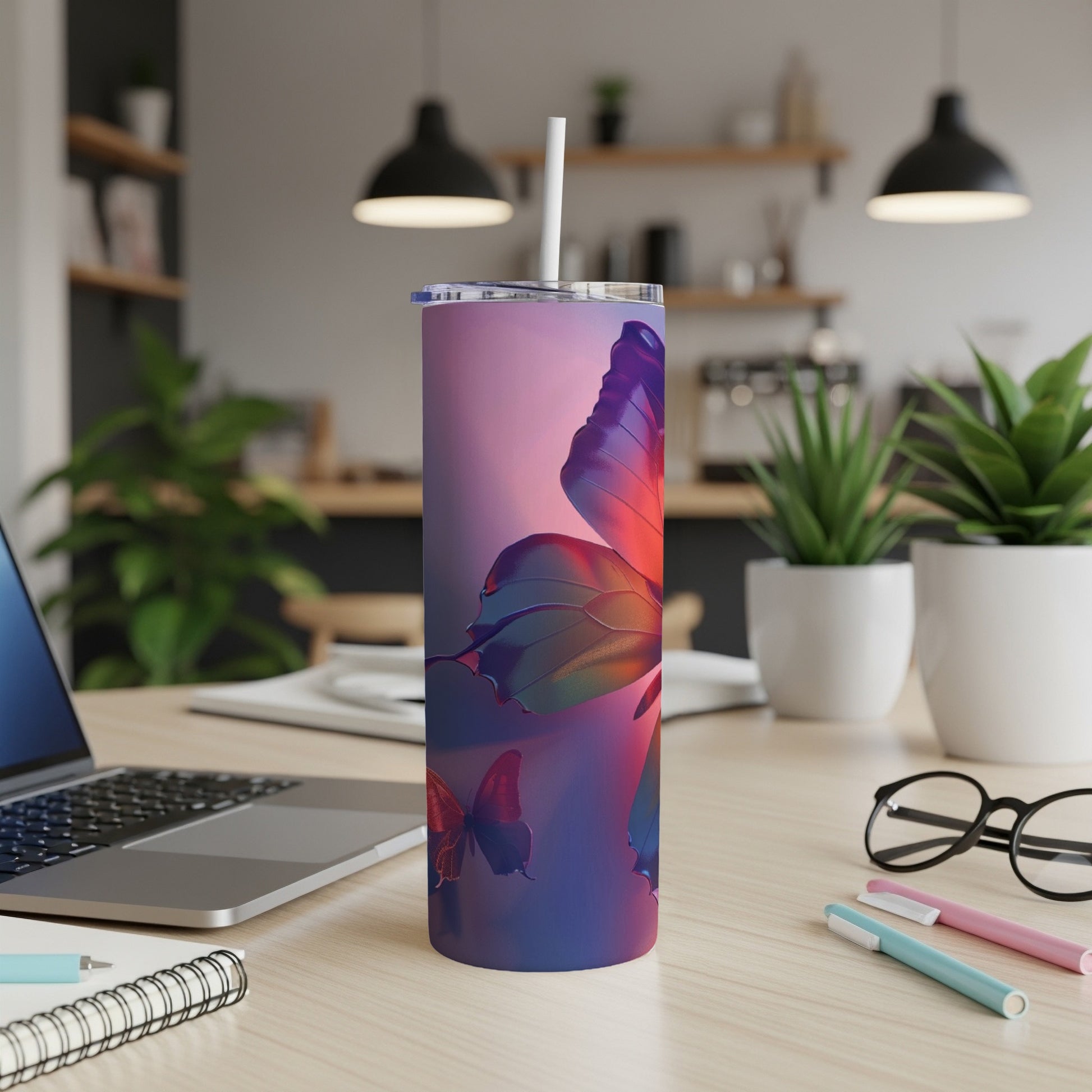 Tumbler with colorful butterfly design on a desk with laptop and pens.