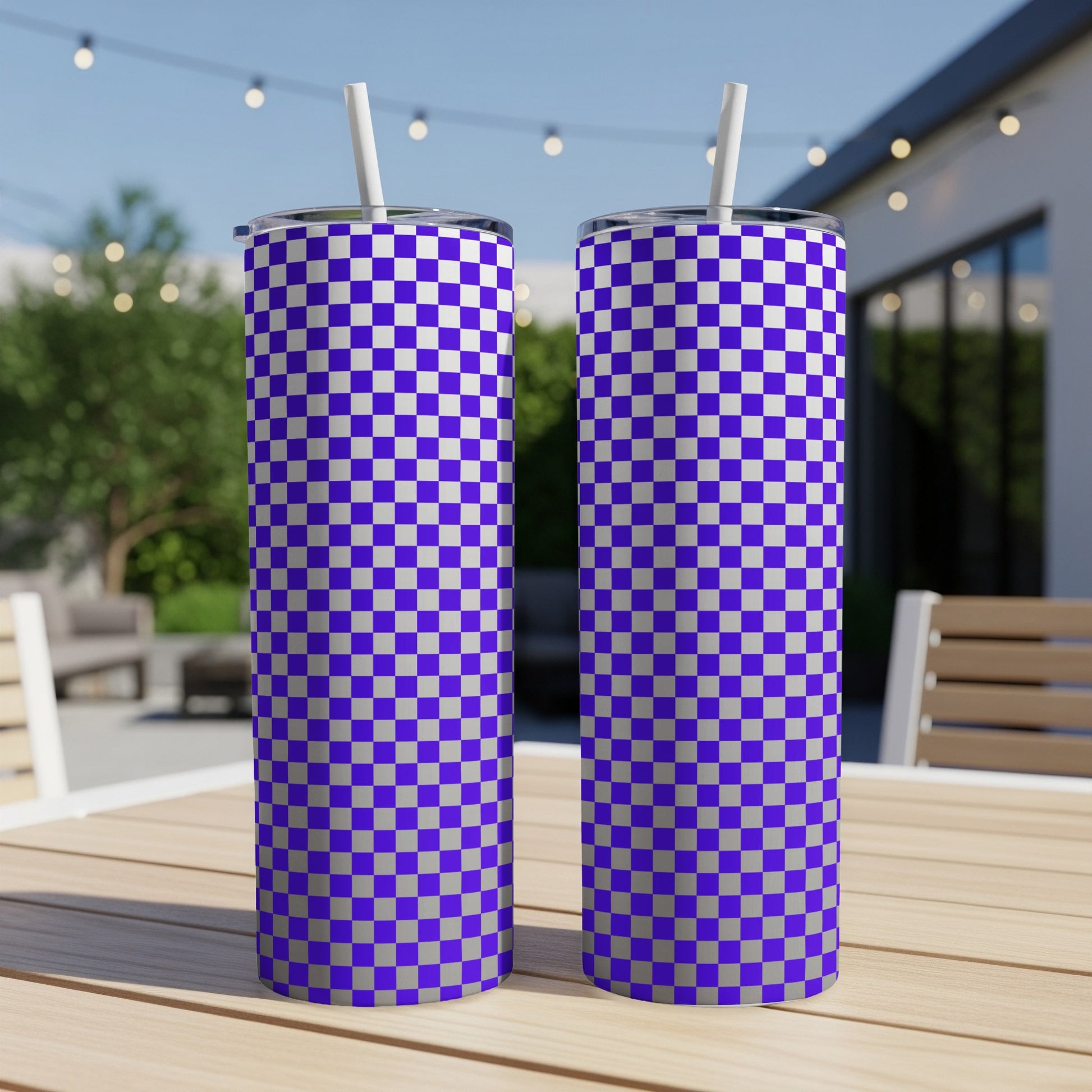 Two purple and white checkered tumblers with straws on a wooden table.