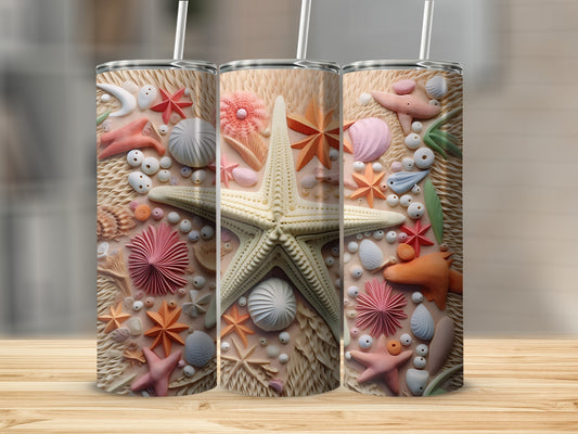 Three tumblers with detailed seashell and starfish embellishments on a wooden surface.