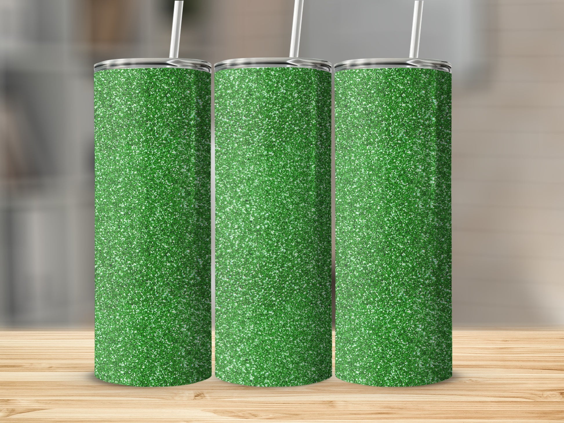 Three green glitter tumblers with white straws on a wooden surface.