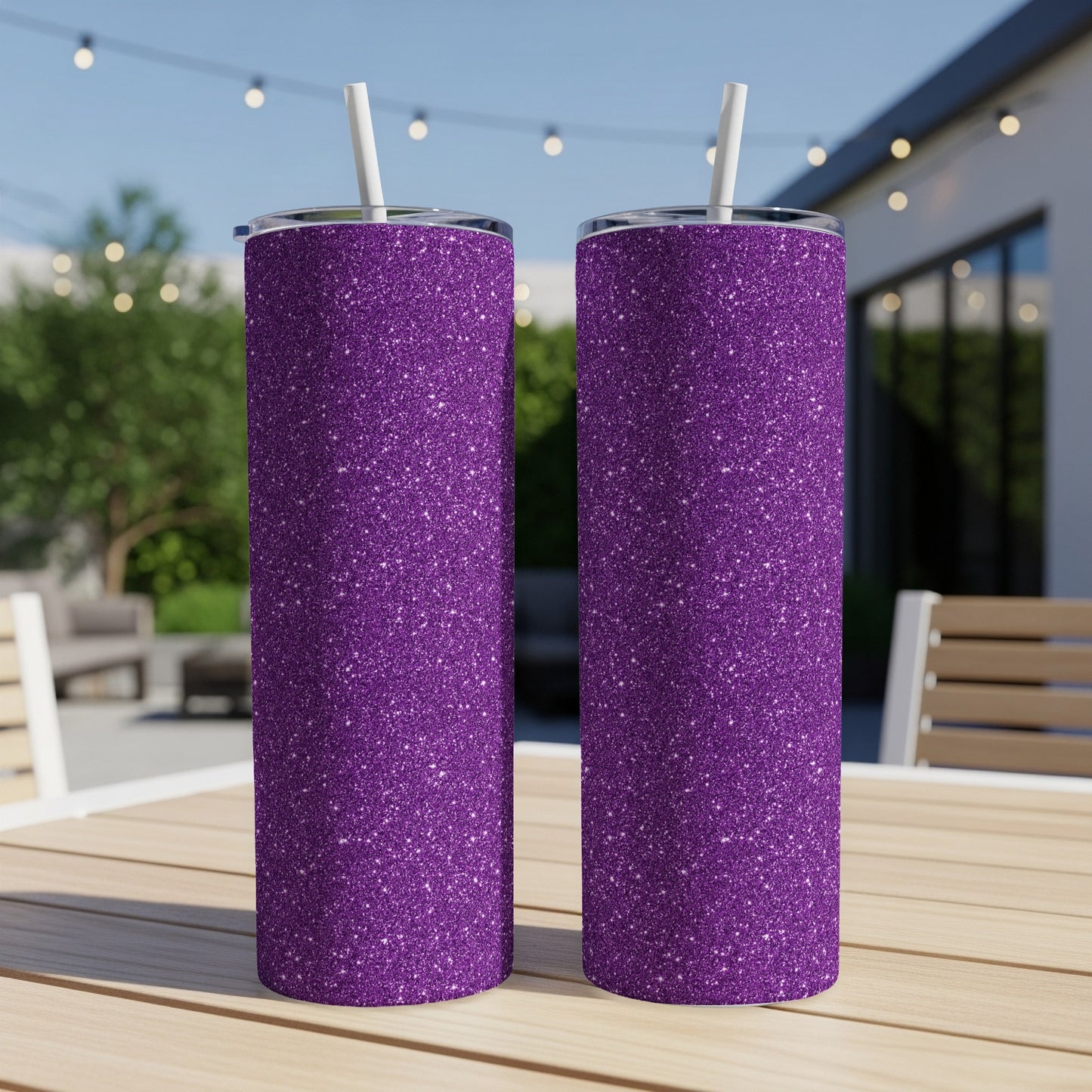 Two purple glitter tumblers with white straws on a wooden table outdoors.