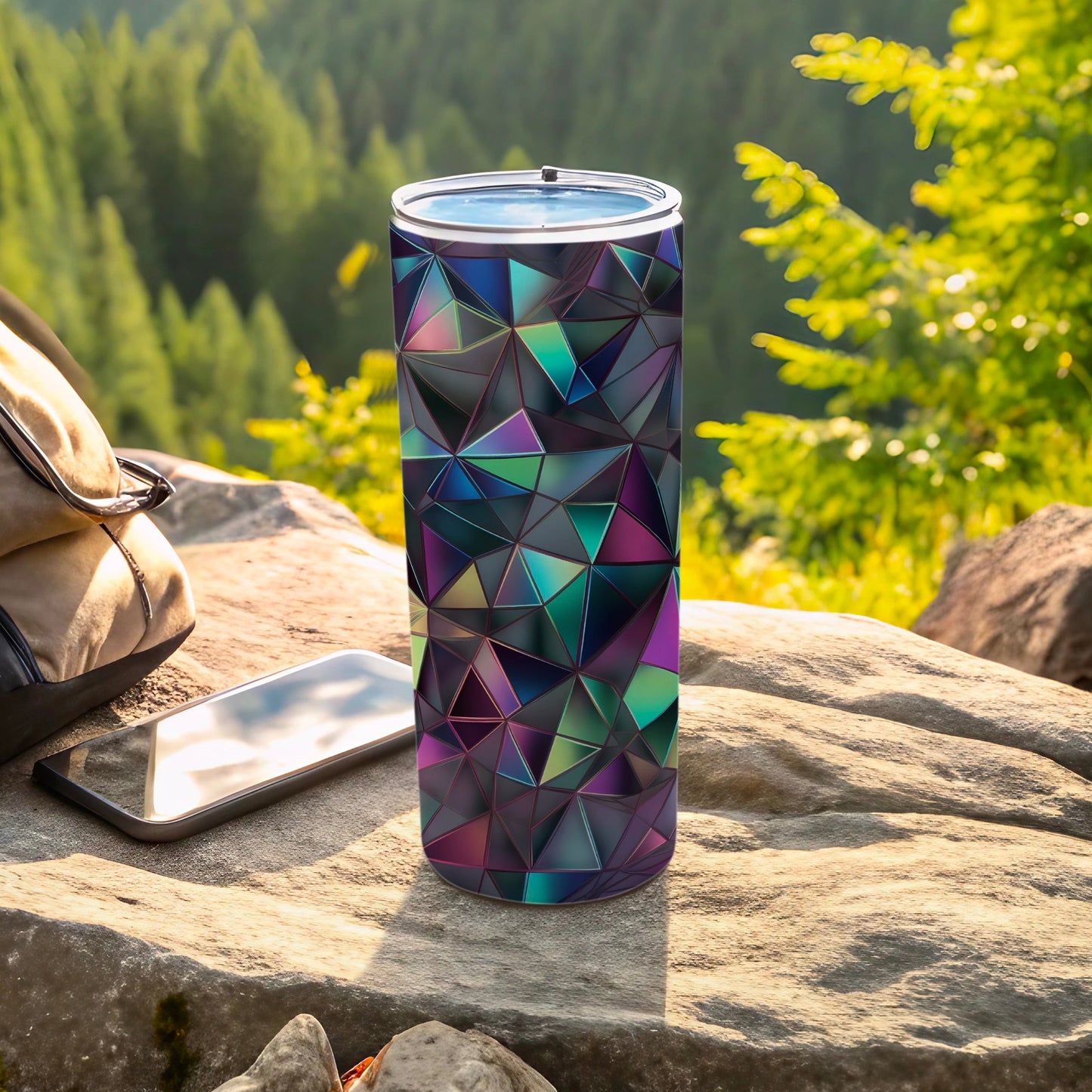 Geometric patterned tumbler on a rock with a phone and backpack.