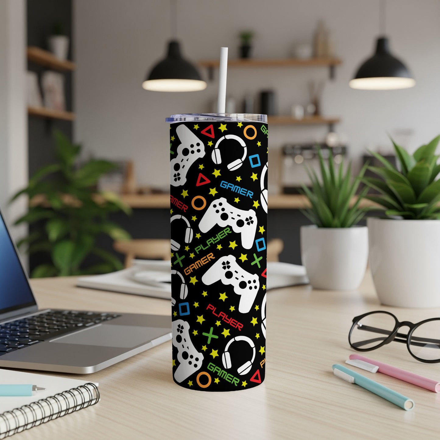 Black tumbler with repeating pattern of video game controllers, headphones, and stars.