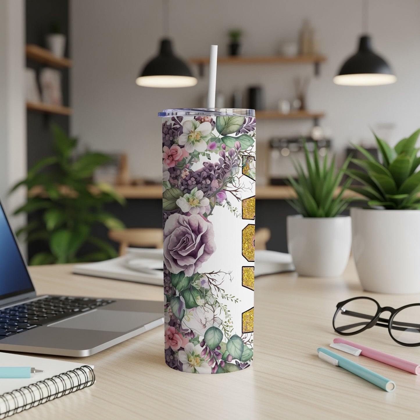 Floral tumbler with straw on a desk next to a laptop.