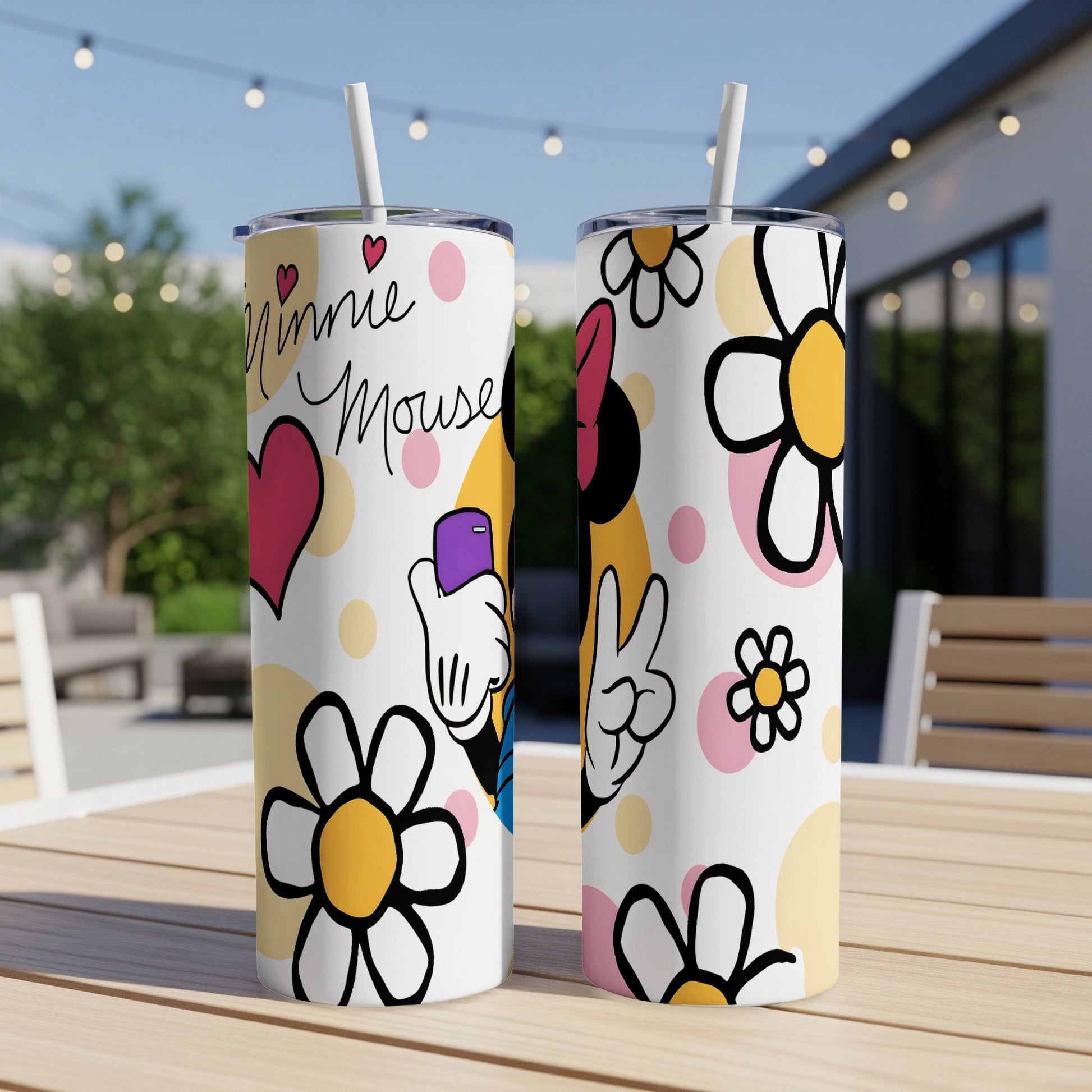 Two Minnie Mouse tumblers with floral patterns and heart accents on a table.