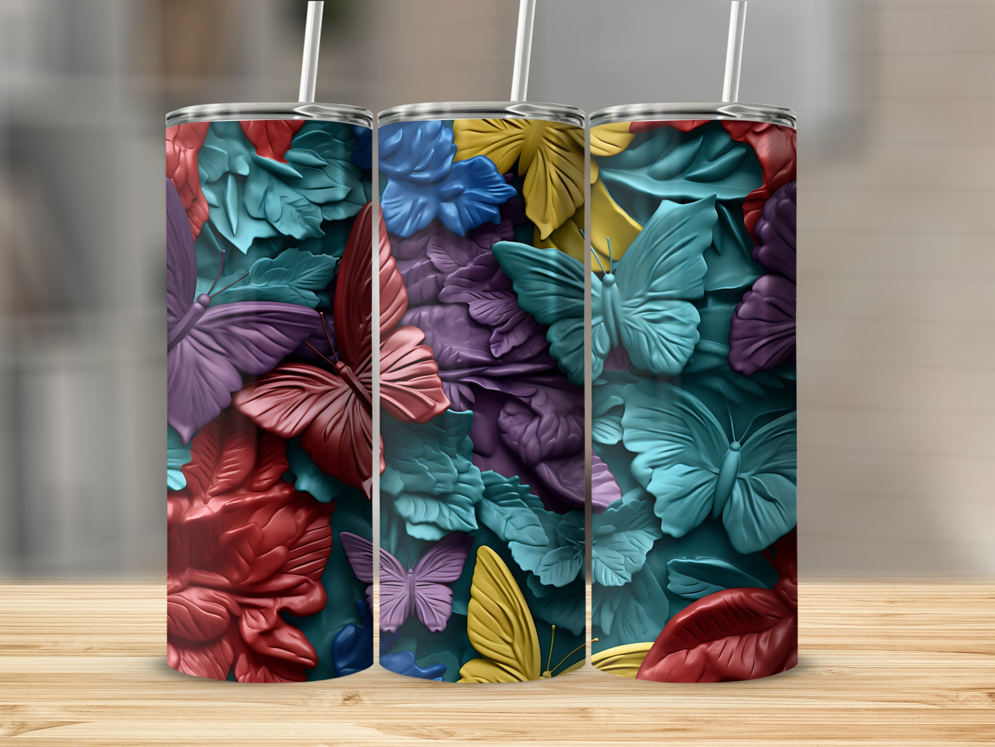 Three colorful tumblers with butterfly and floral embossed designs.