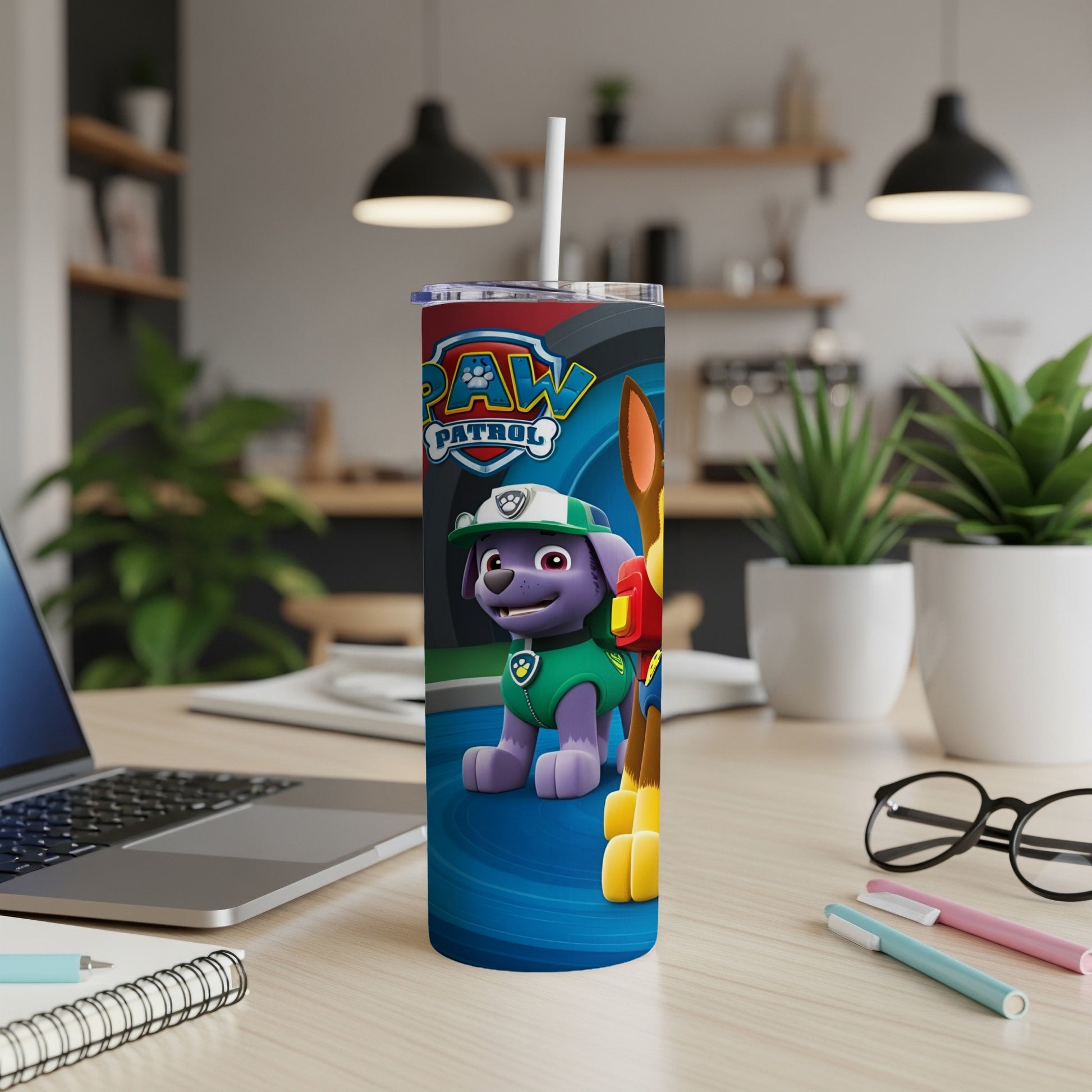 Chase from Paw Patrol on a blue tumbler with a straw on a desk.