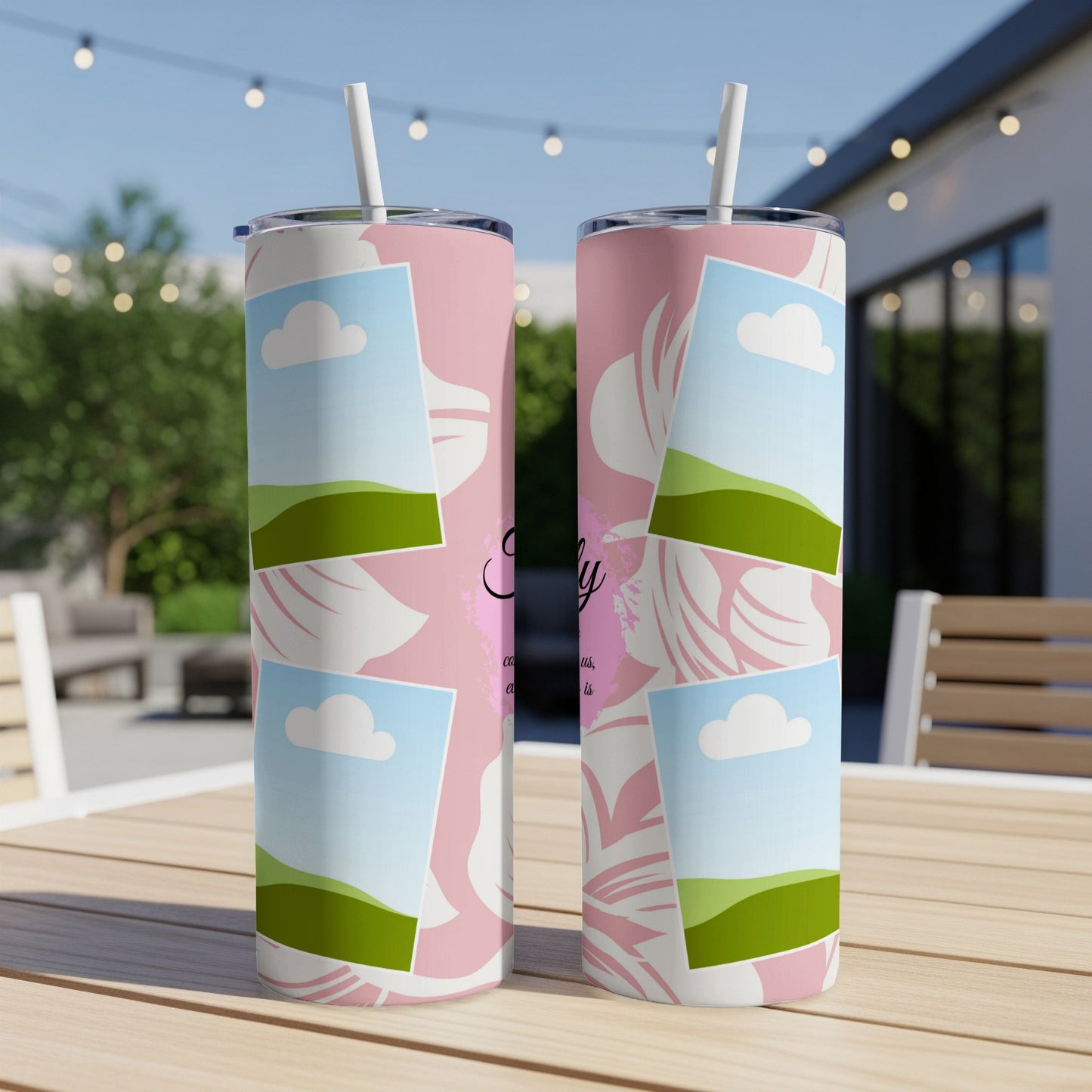 Two pink floral tumblers with landscape photo frames and straws on a wooden table.