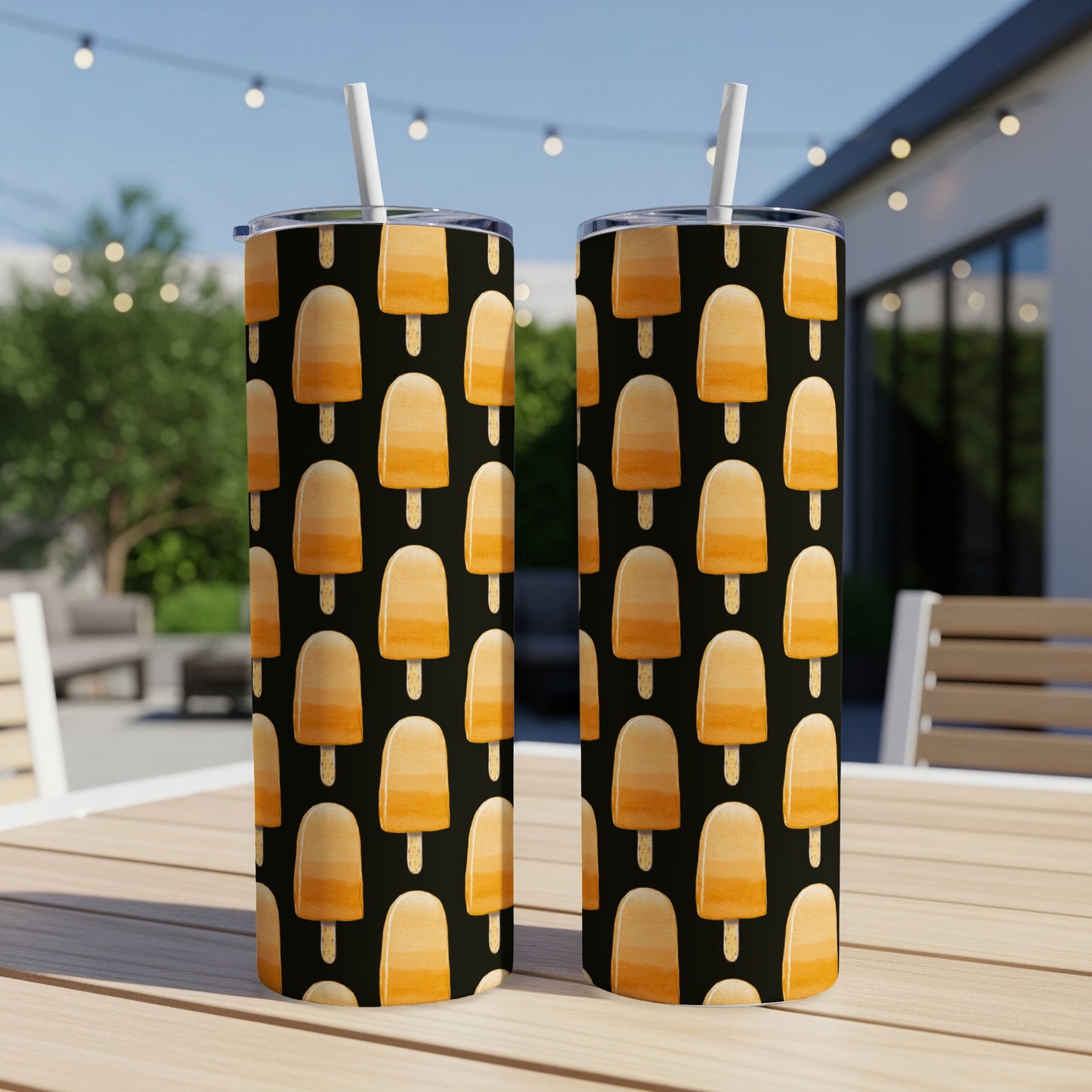 Two tumblers with a repeating pattern of orange popsicles on a black background.