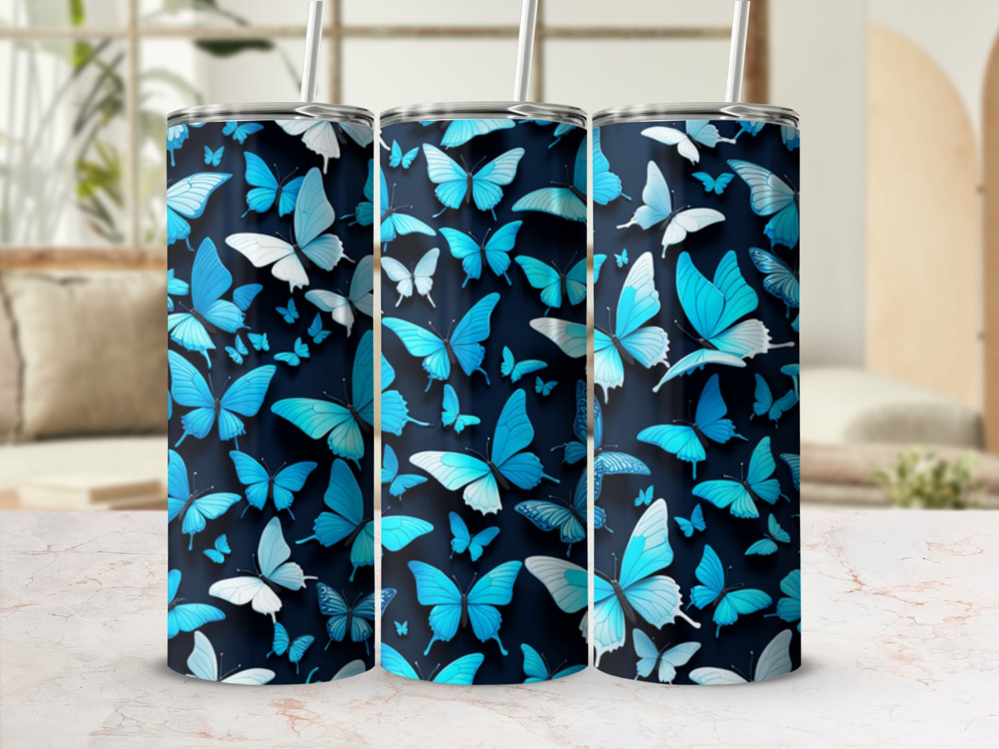 Three tumblers with blue butterfly designs on a marble surface.