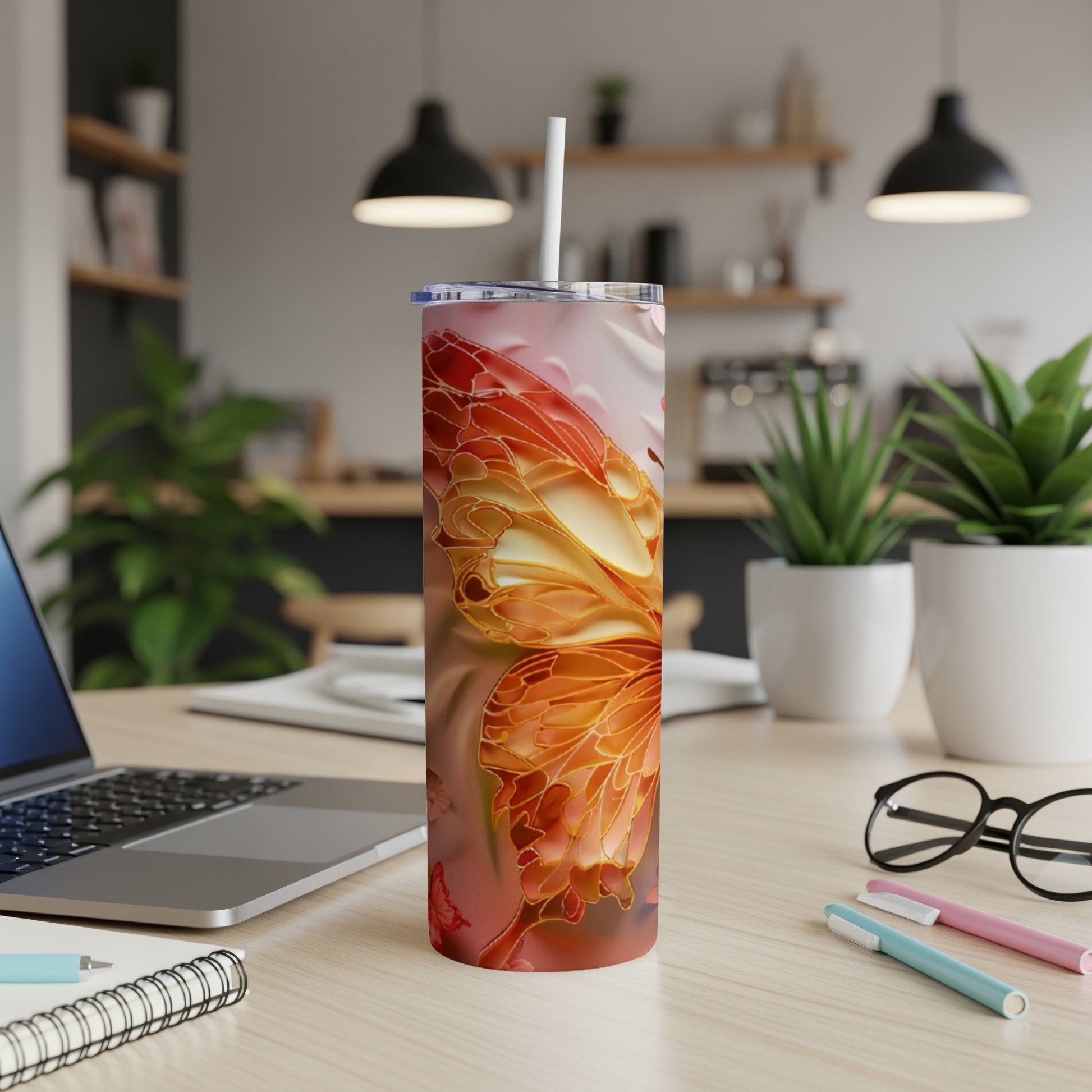 Tall tumbler with orange and red butterfly wing design, on a desk.