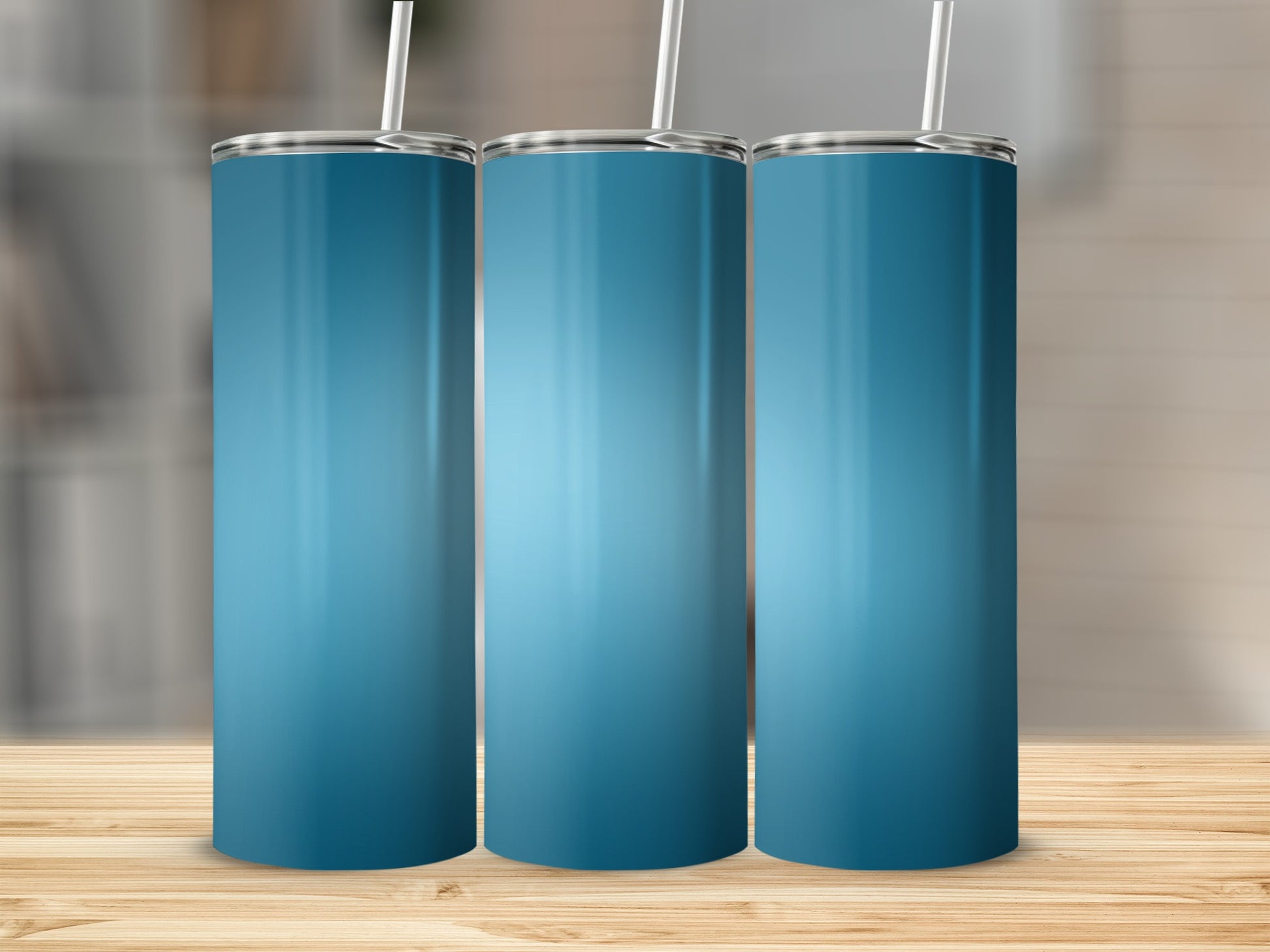 Three blue gradient tumblers with straws on a wooden surface.