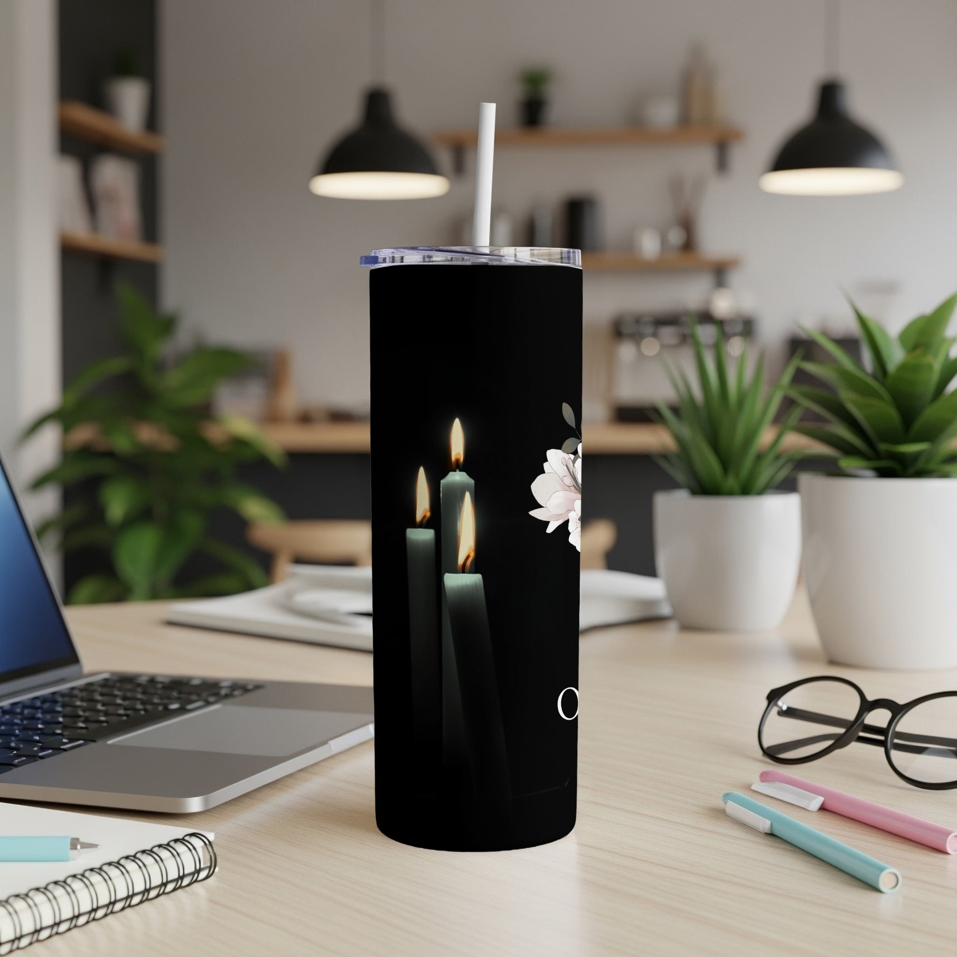 Black tumbler with lit candles and pale pink flowers design, white straw.