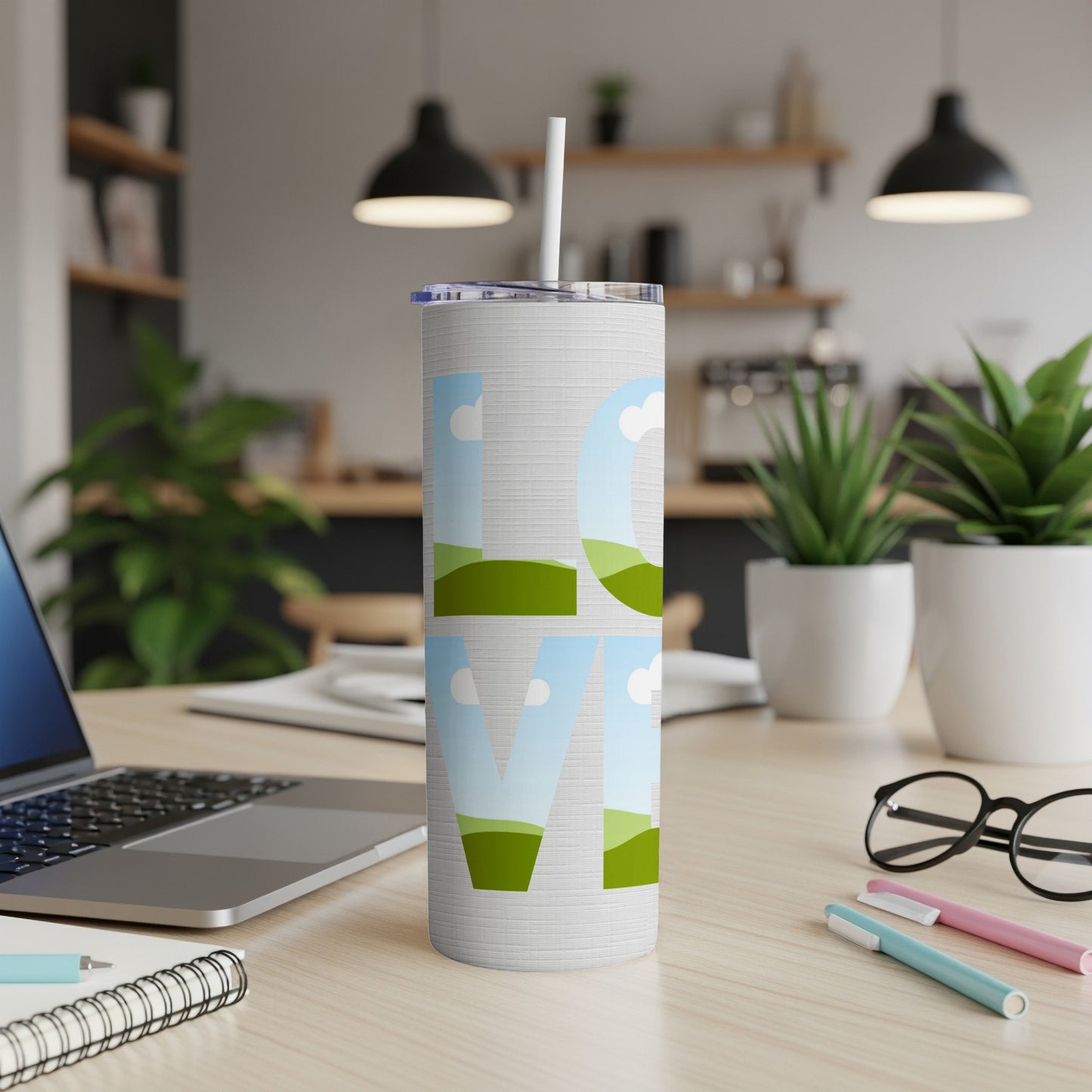 White tumbler with "LOVE" text filled with sky and rolling hills.