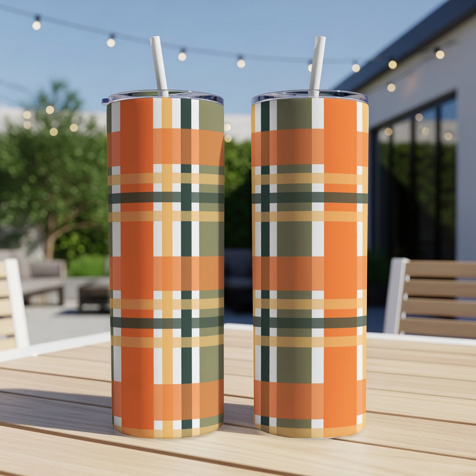 Two tumblers with orange, green, and beige plaid pattern on an outdoor table.