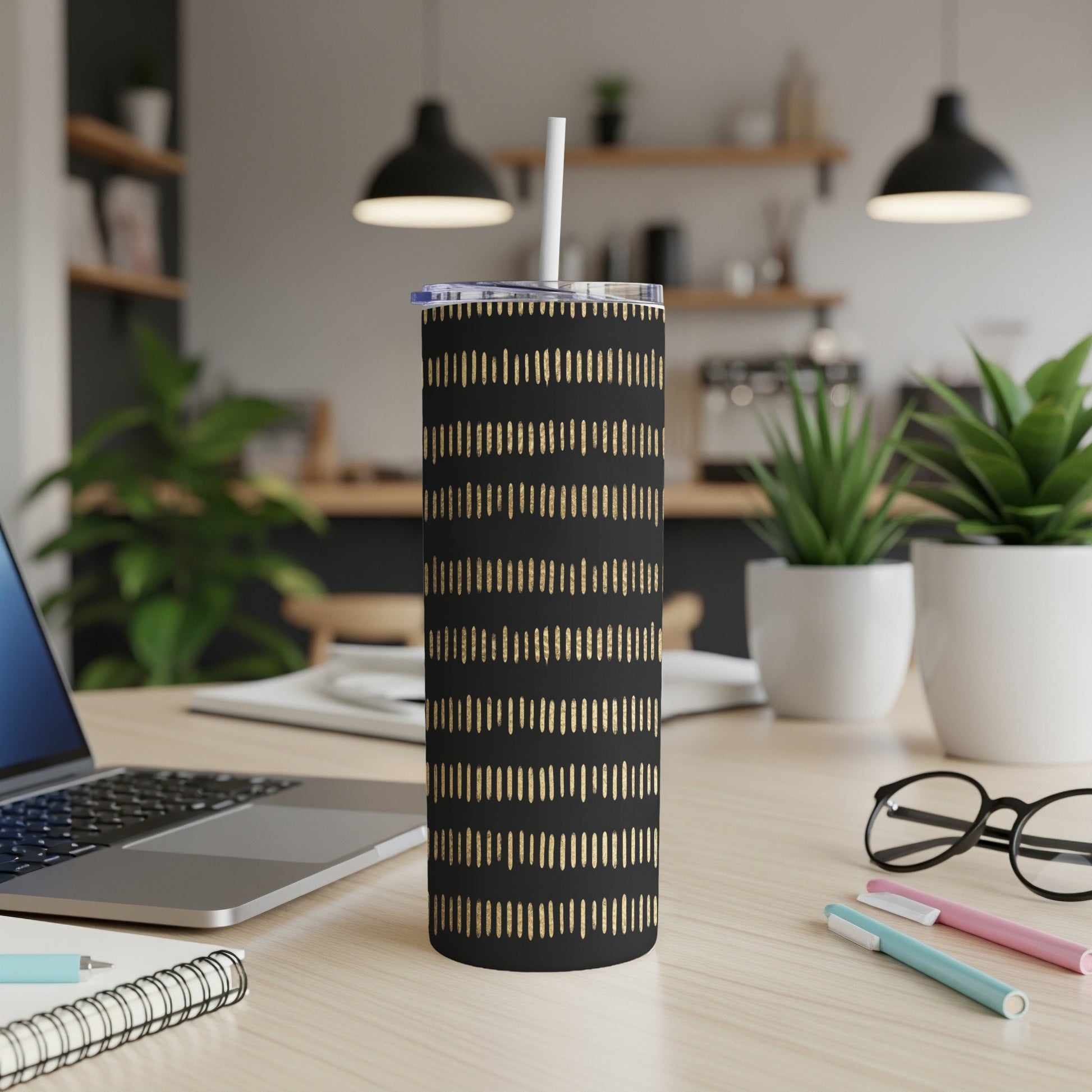 Black tumbler with gold dashed pattern and white straw on a desk.