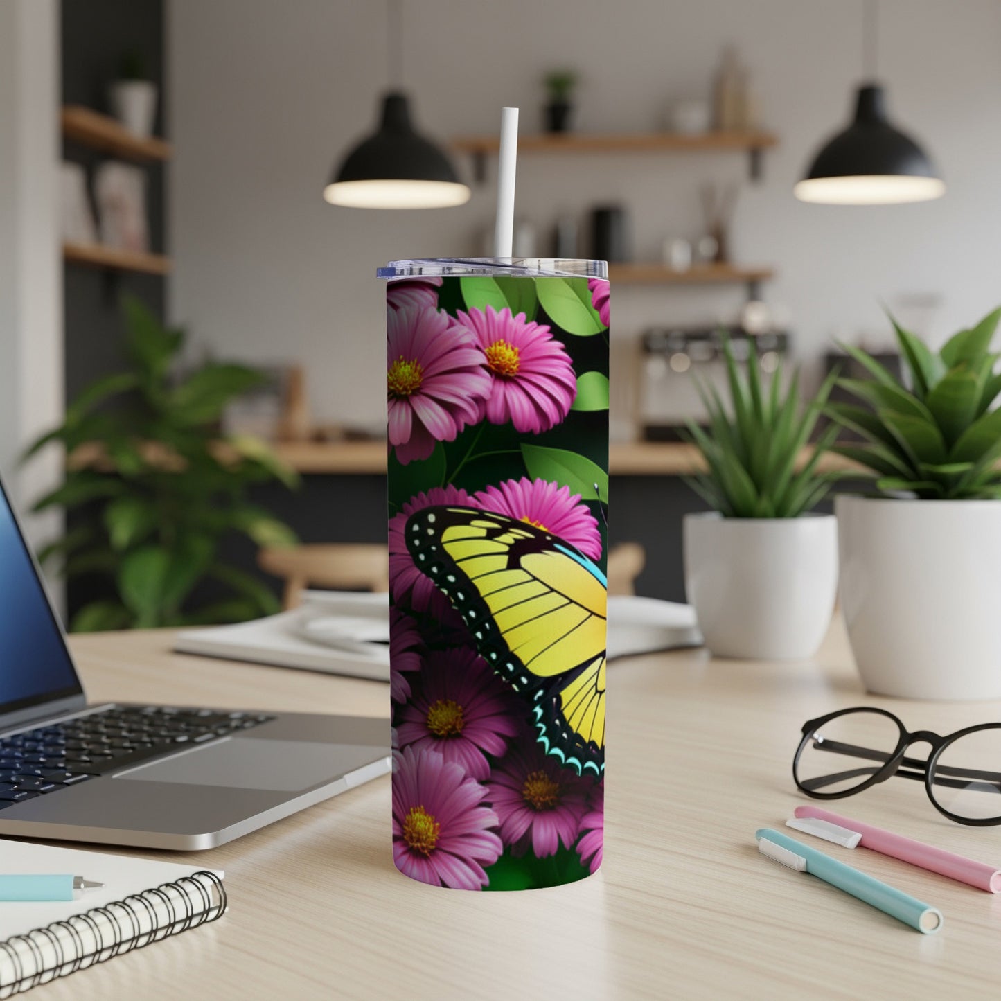 Yellow butterfly on pink flowers, with straw in a tumbler, on a desk.