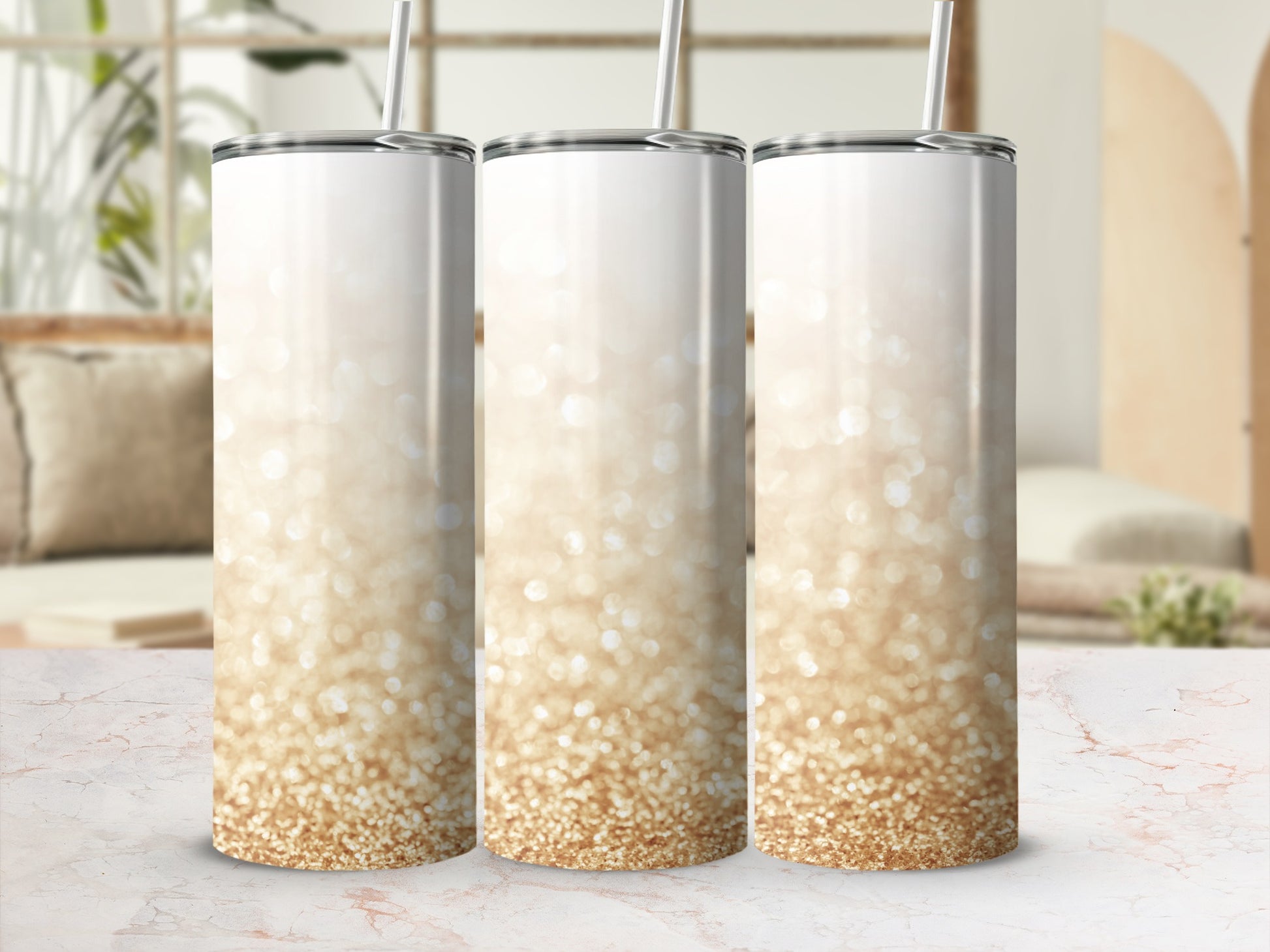 Three tumblers with gold glitter gradient on a marble surface.
