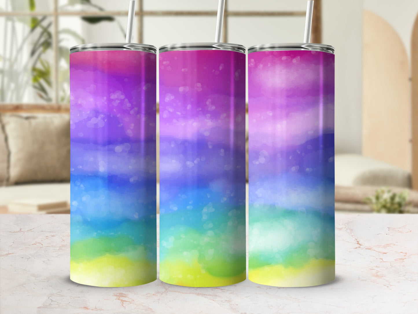 Three tumblers with watercolor rainbow patterns and white straws.