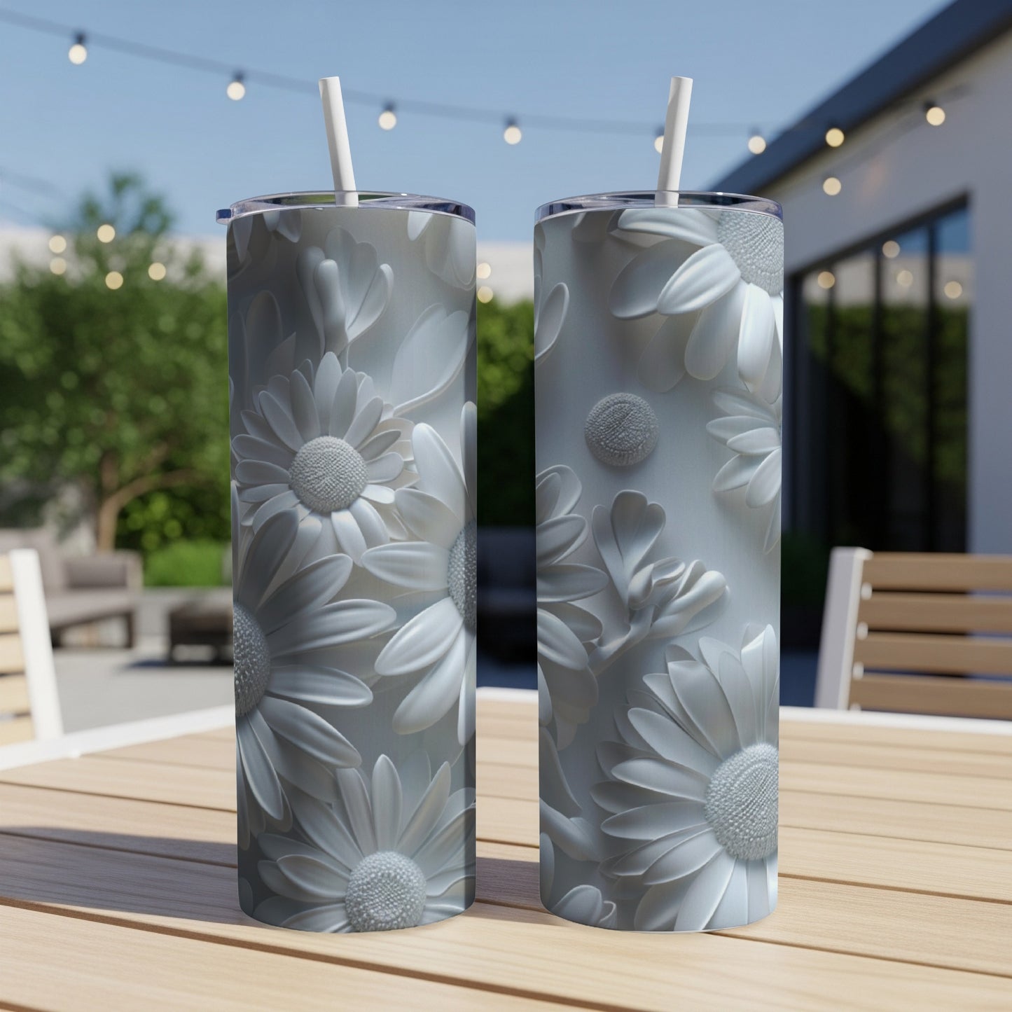 Two white tumblers with embossed floral patterns sit on a wooden table outdoors.