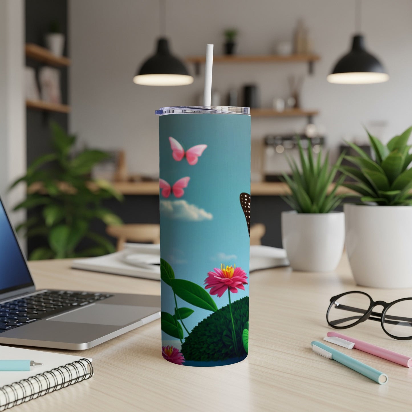 Blue butterfly and pink flower on a tumbler with a laptop and desk items.