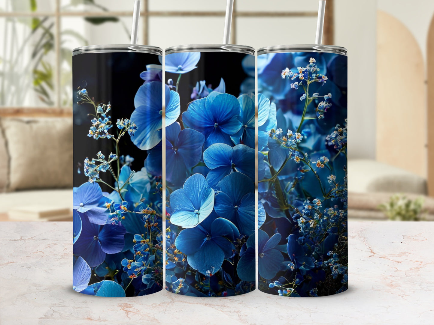 Three blue floral tumblers with straws, set against a blurred background.