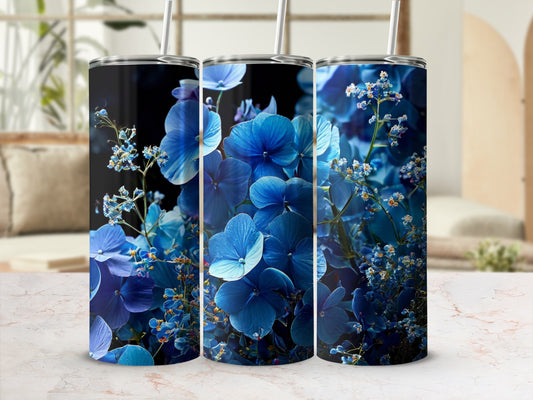 Three blue floral tumblers with straws, set against a blurred background.