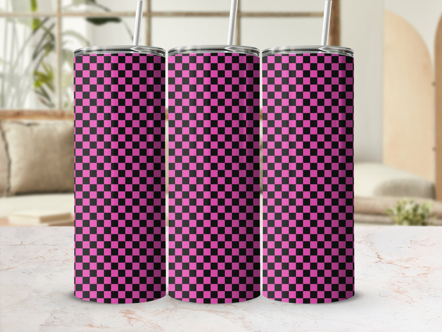 Three pink and black checkered tumblers with straws on a marble surface.
