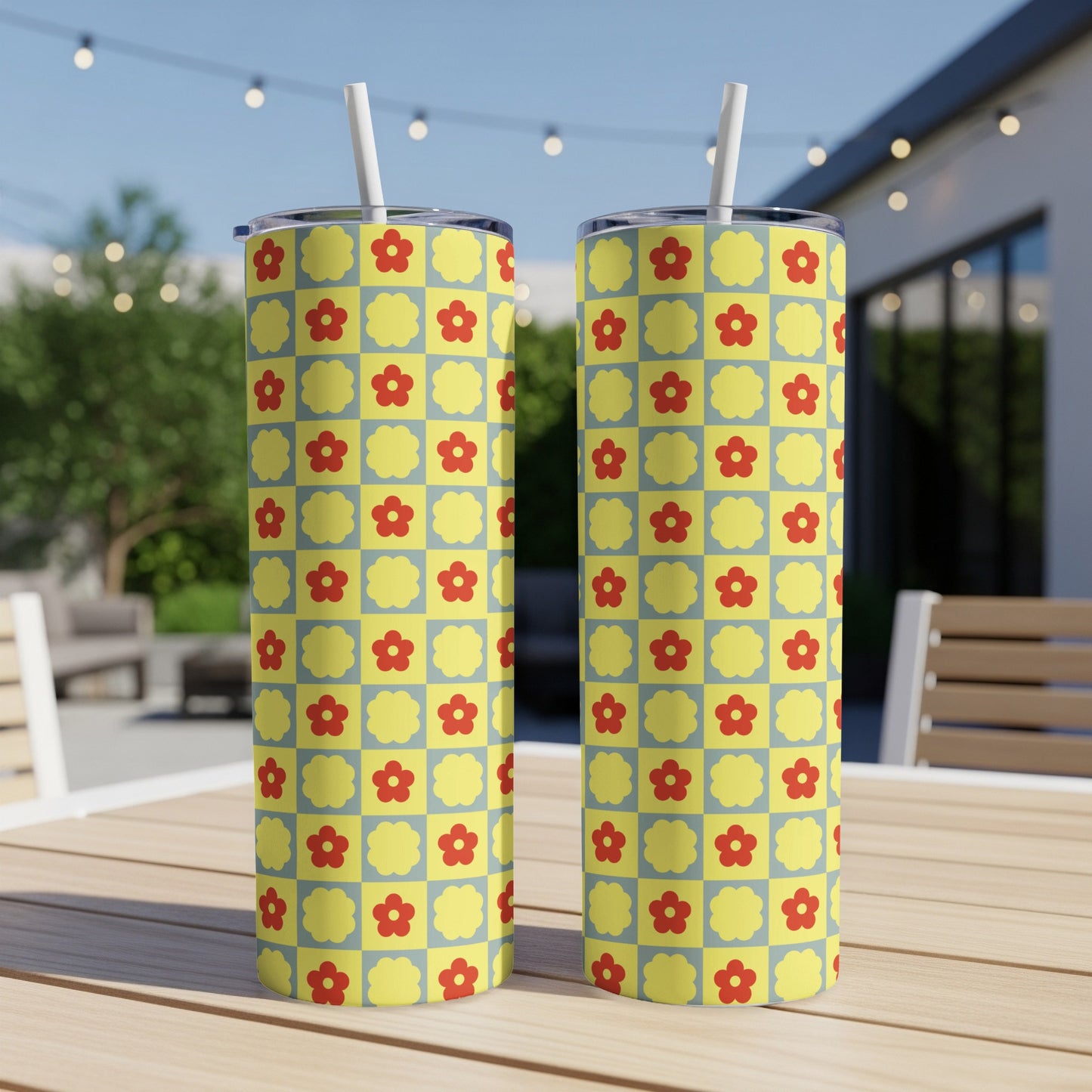 Two yellow tumblers with a repeating red floral pattern on a blue grid.