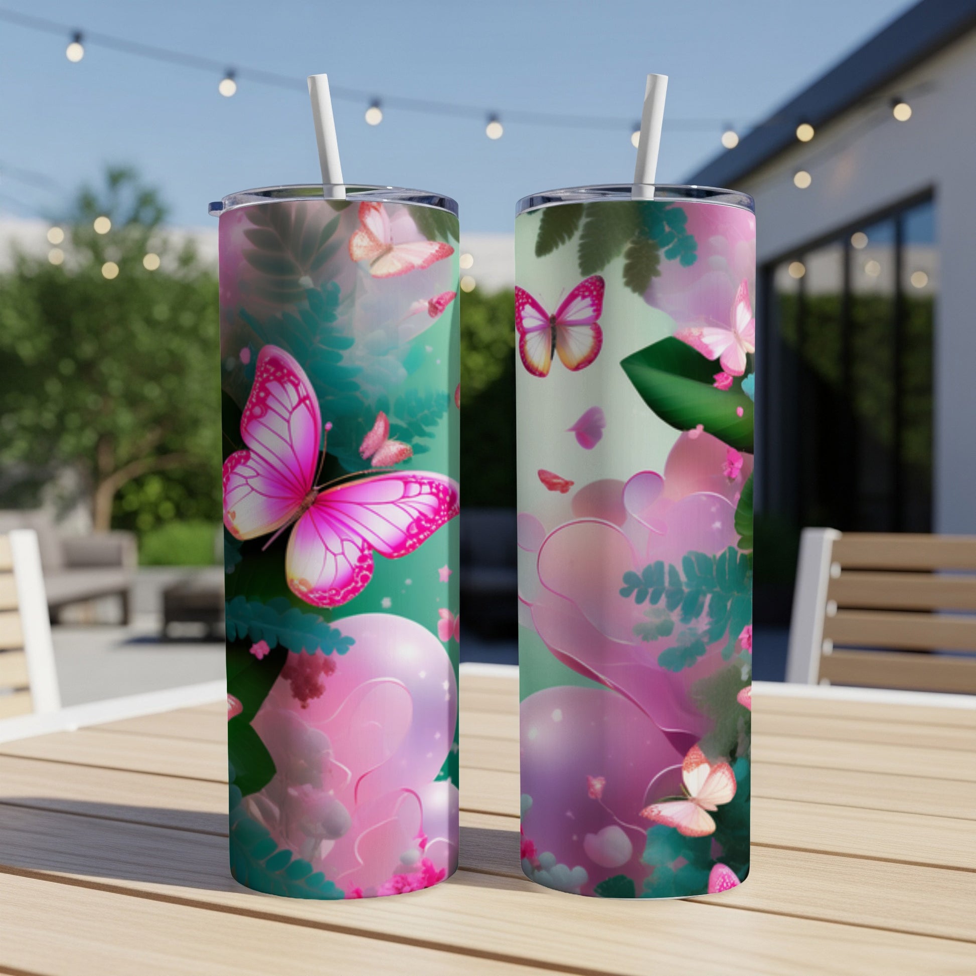 Two tumblers with pink butterflies and green foliage on a table outdoors.