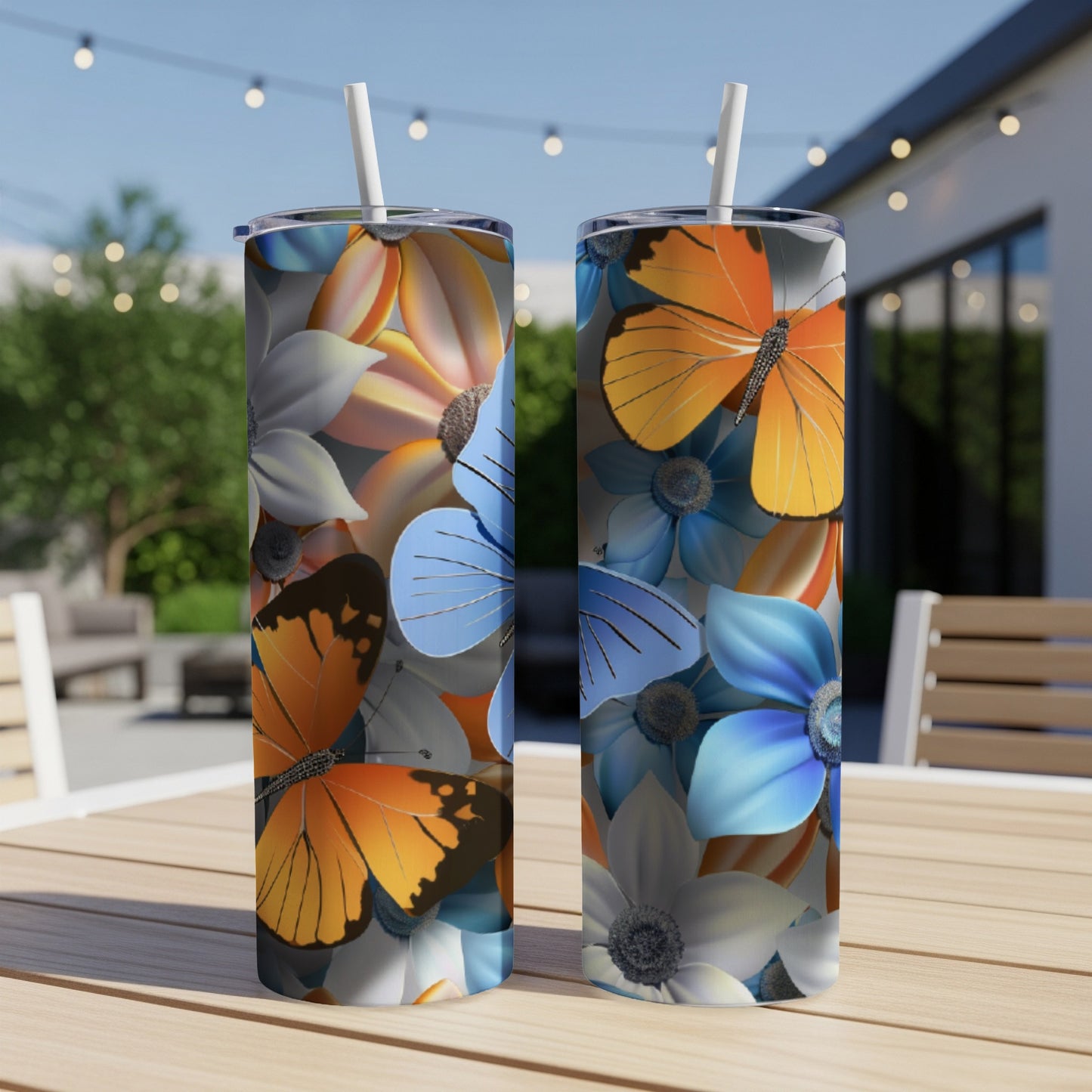 Two tumblers with floral and butterfly designs on a wooden table outdoors.