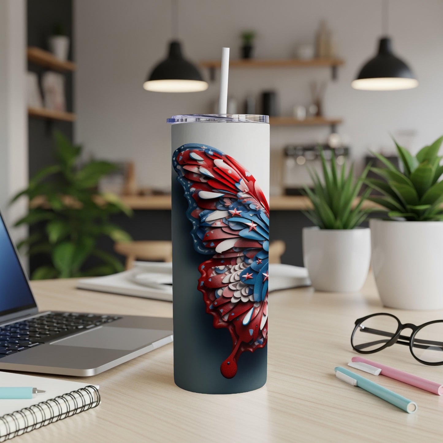 Tall tumbler with a butterfly wing design, on a desk.